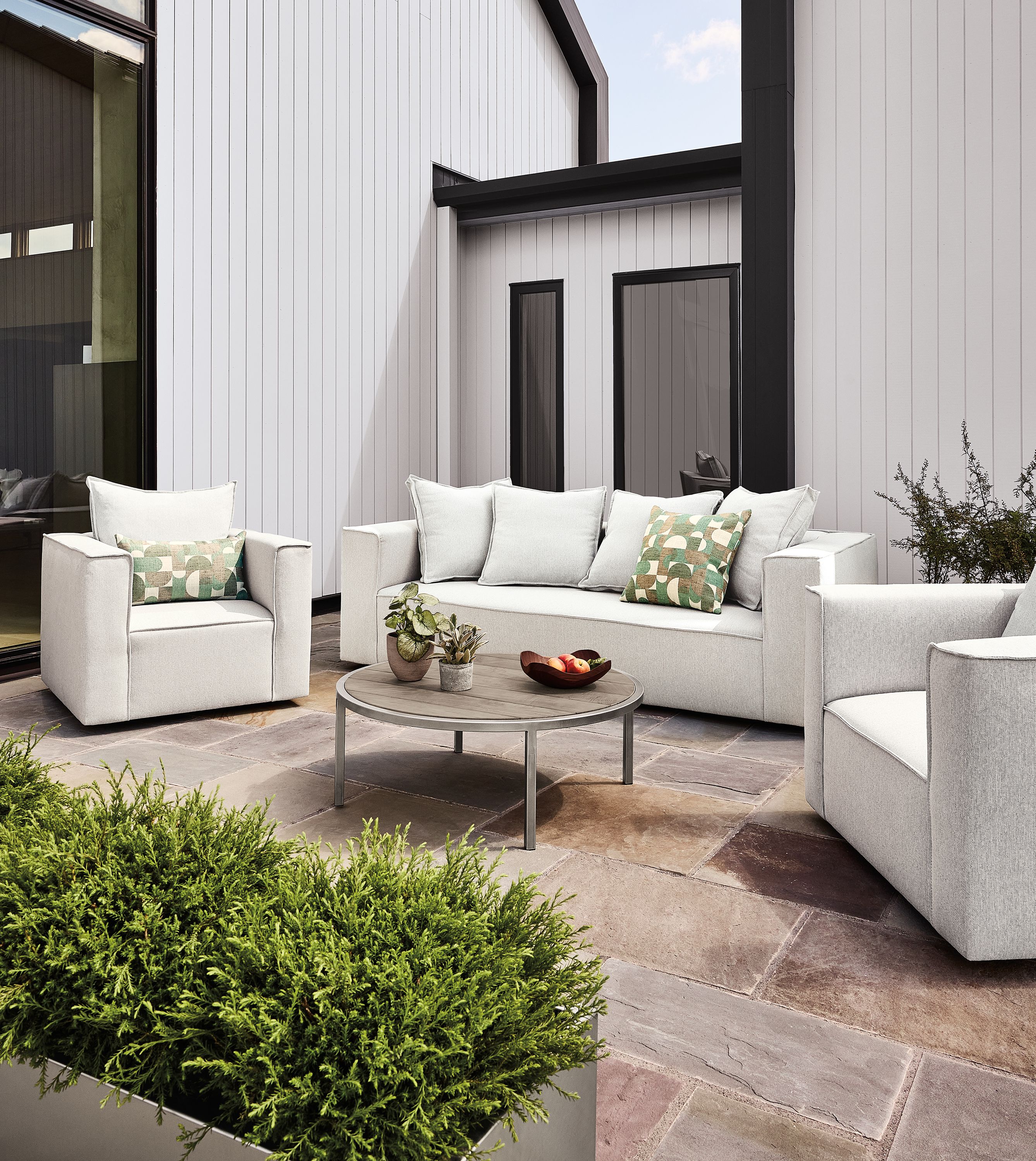 Patio with oasis sofa, 2 swivel chairs, 2 square ottomans in mist grey and a montego table in aged thermally modified oak.