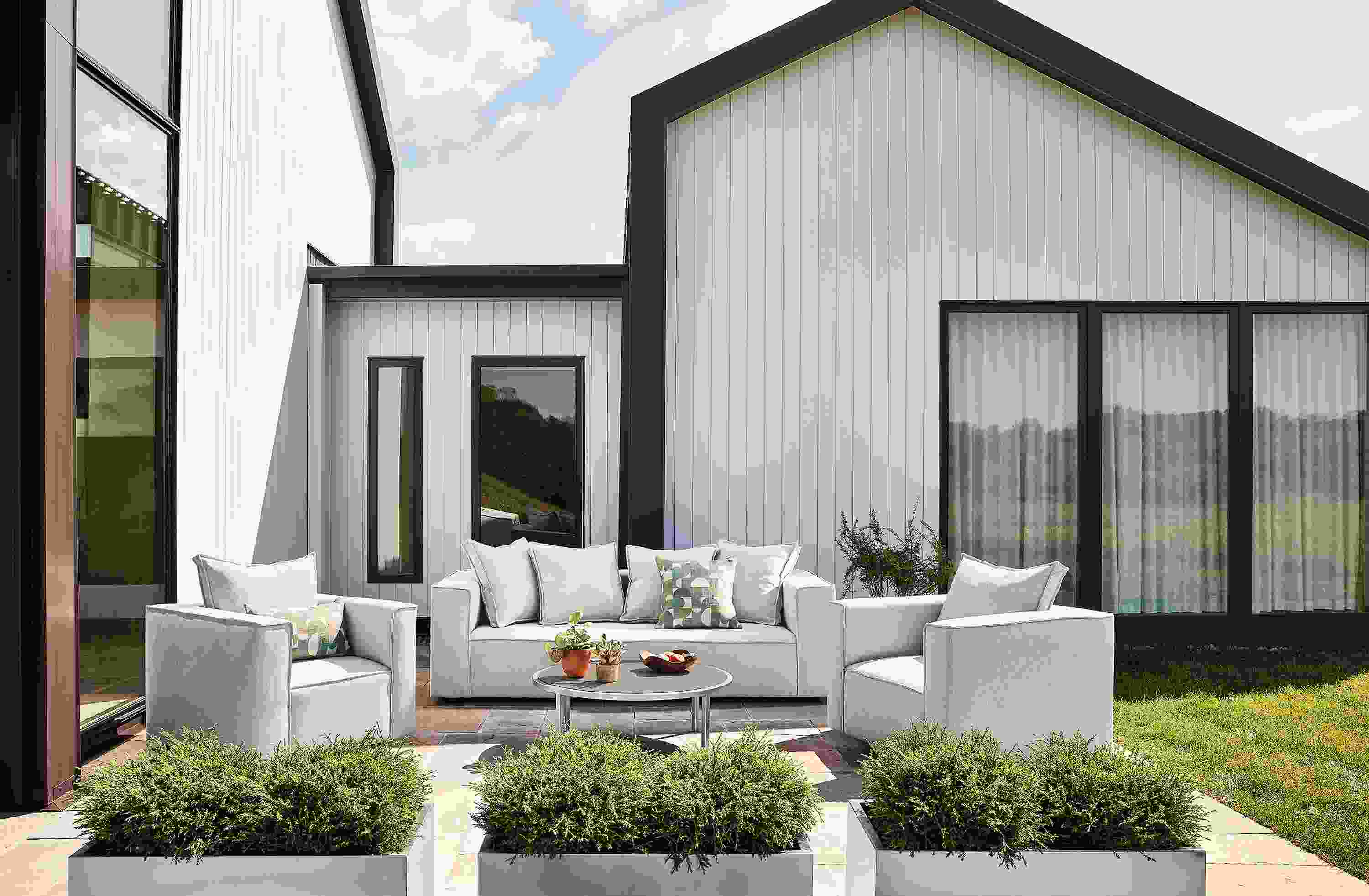 Patio with oasis sofa, 2 oasis swivel chairs and 2 oasis square ottomans all in mist grey fabric and Montego table in aged thermally modified oak.