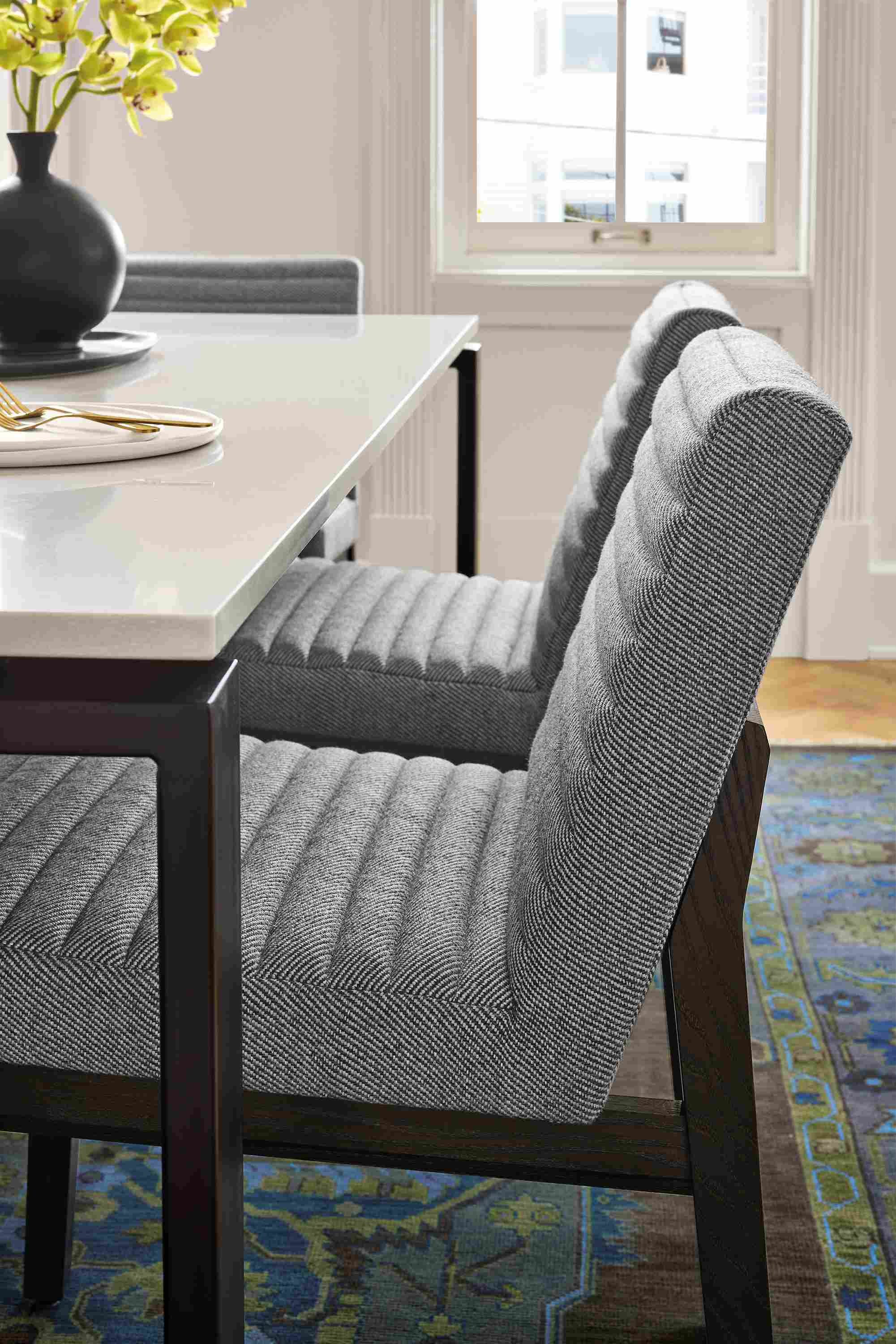Dining room with detail of 3 olsen side chairs in derry graphite and rand table in natural steel with light grey quartz top.