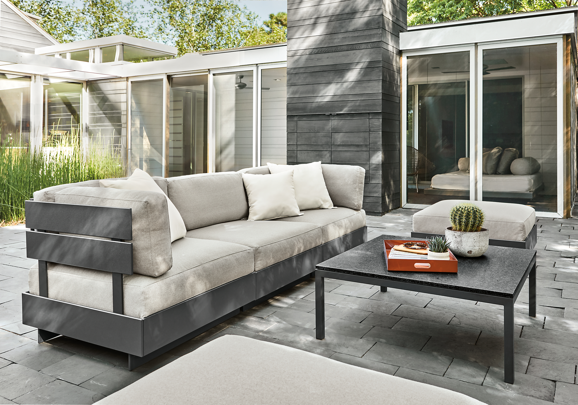 Outdoor patio setting with Omni Three-Piece Modular Sofa and Ottoman with a Pratt Outdoor Coffee Table.