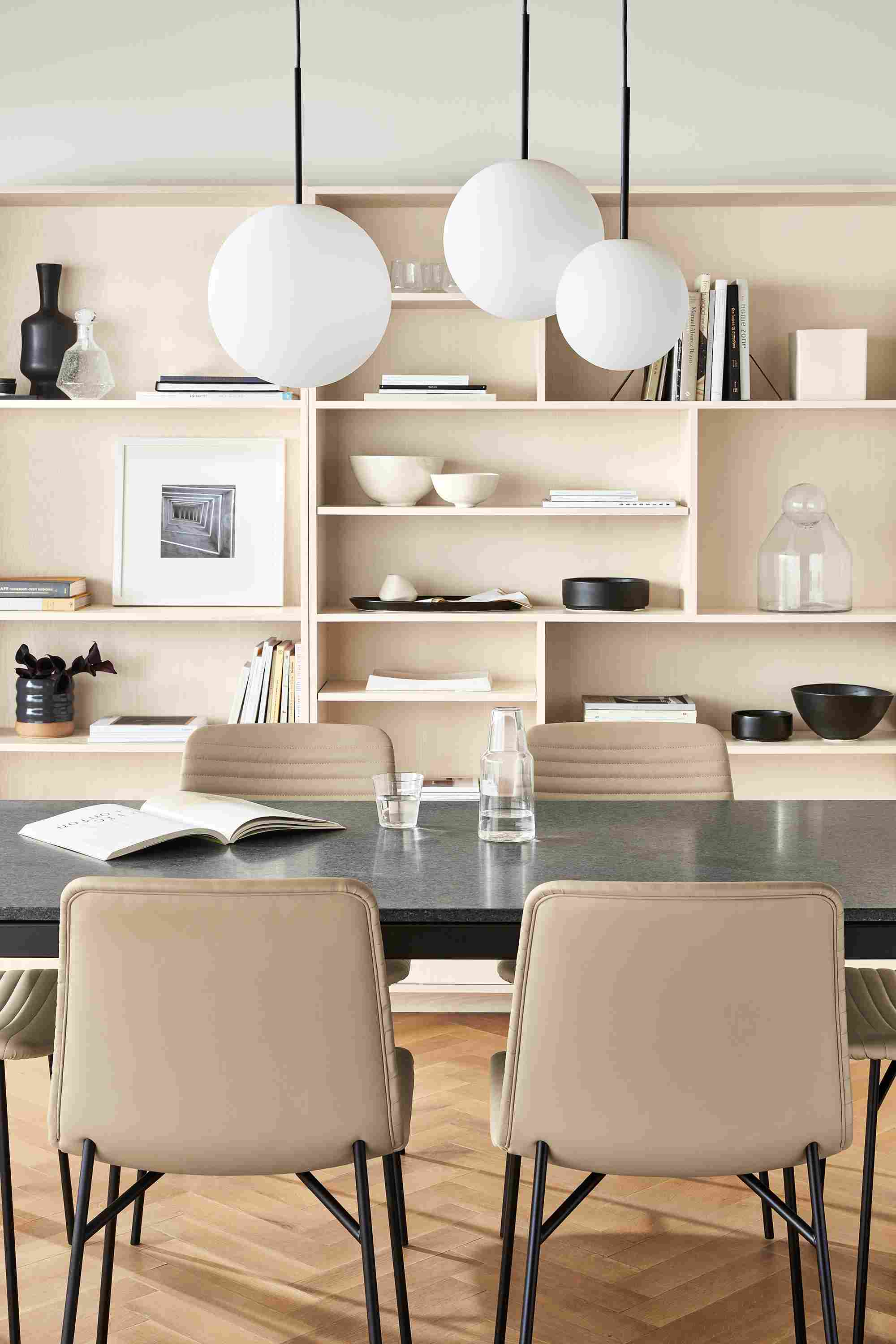 Room setting with Orbit pendants and Parsons table with Keaton bookcases in Sand.