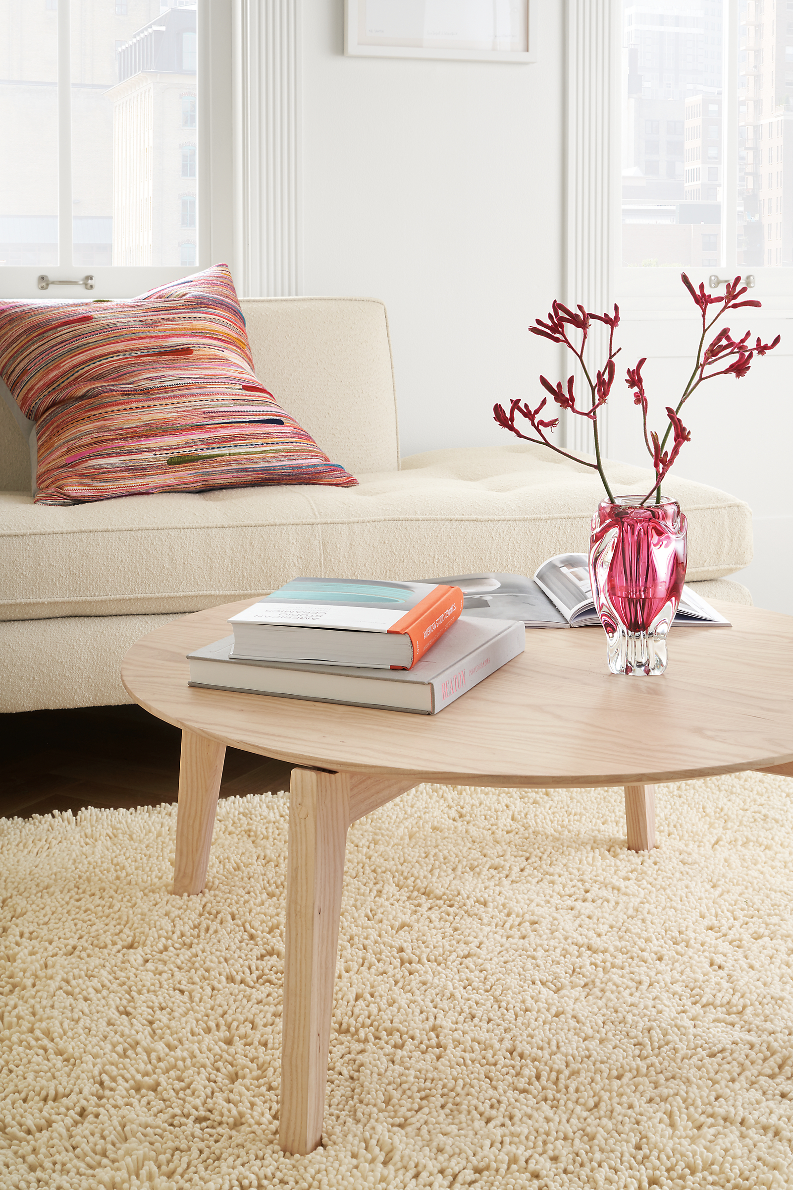 Close-up of an Orlin Round Coffee Table and a Reese Left-Back sofa on an Arden rug in Winter White.