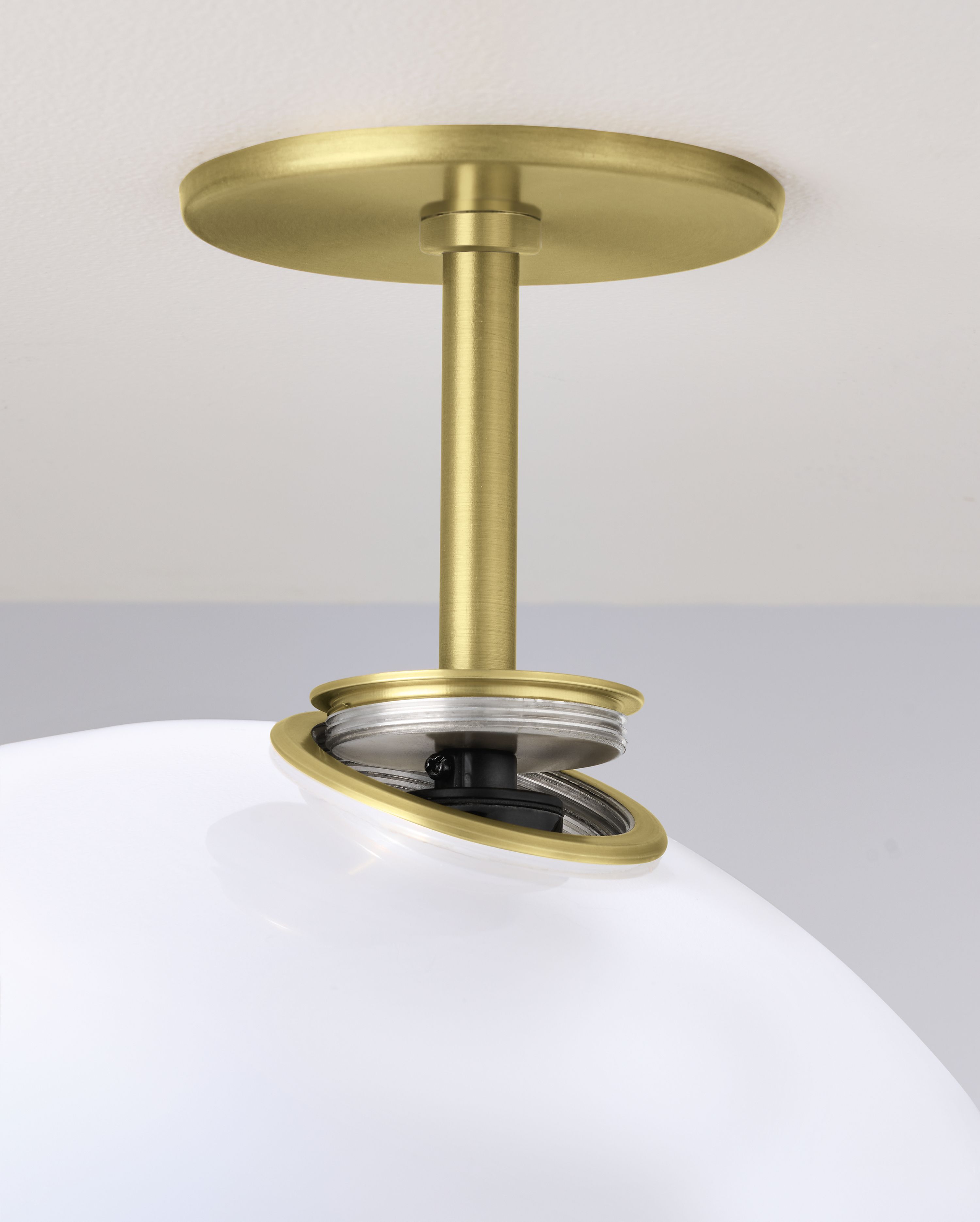 Close up of ceiling plate and screw mount on an Osiris lighting pendant in brushed gold powdercoat and opal glass.