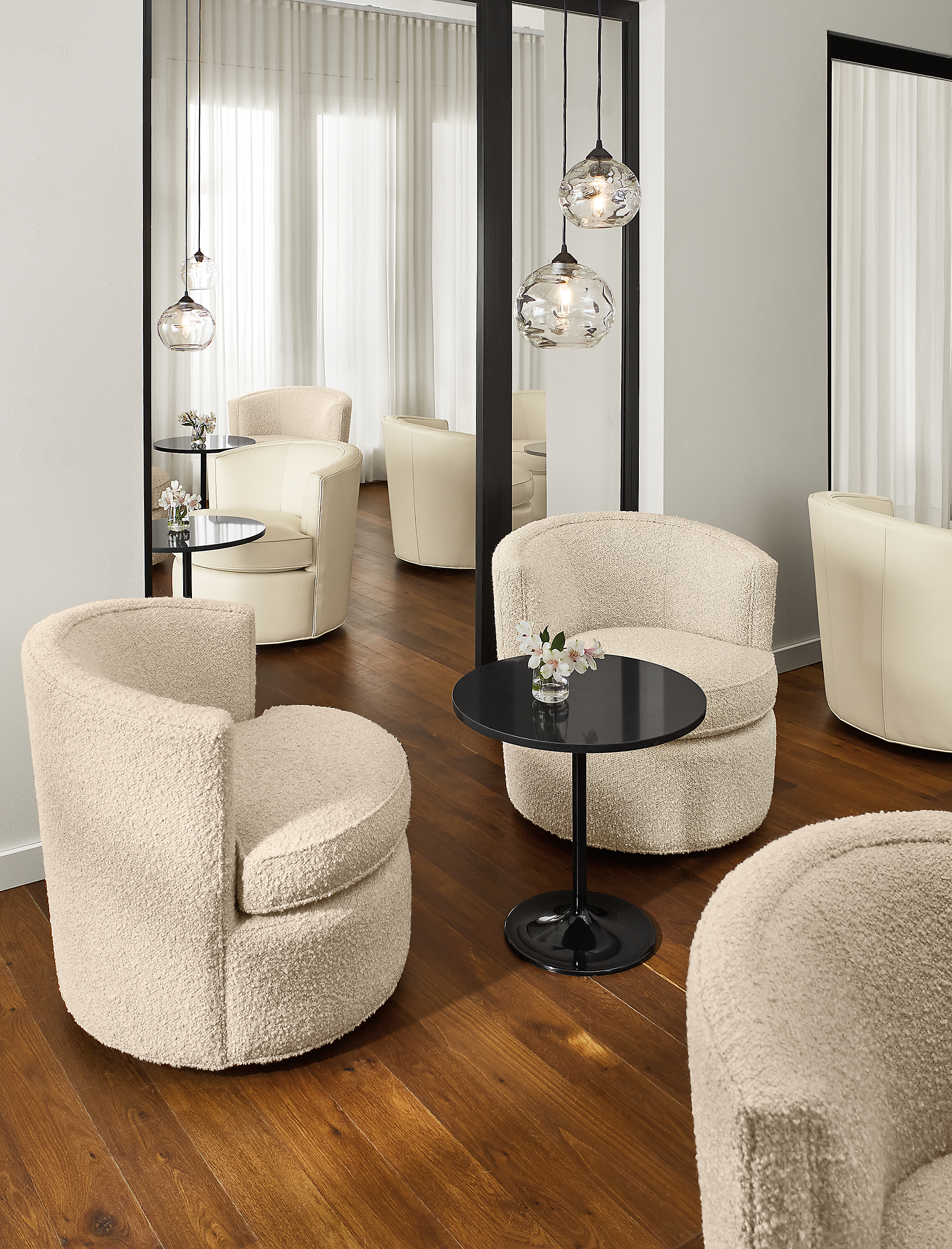 Social setting of multiple Otis swivel chairs in ivory leather and fabric and Aria end tables.