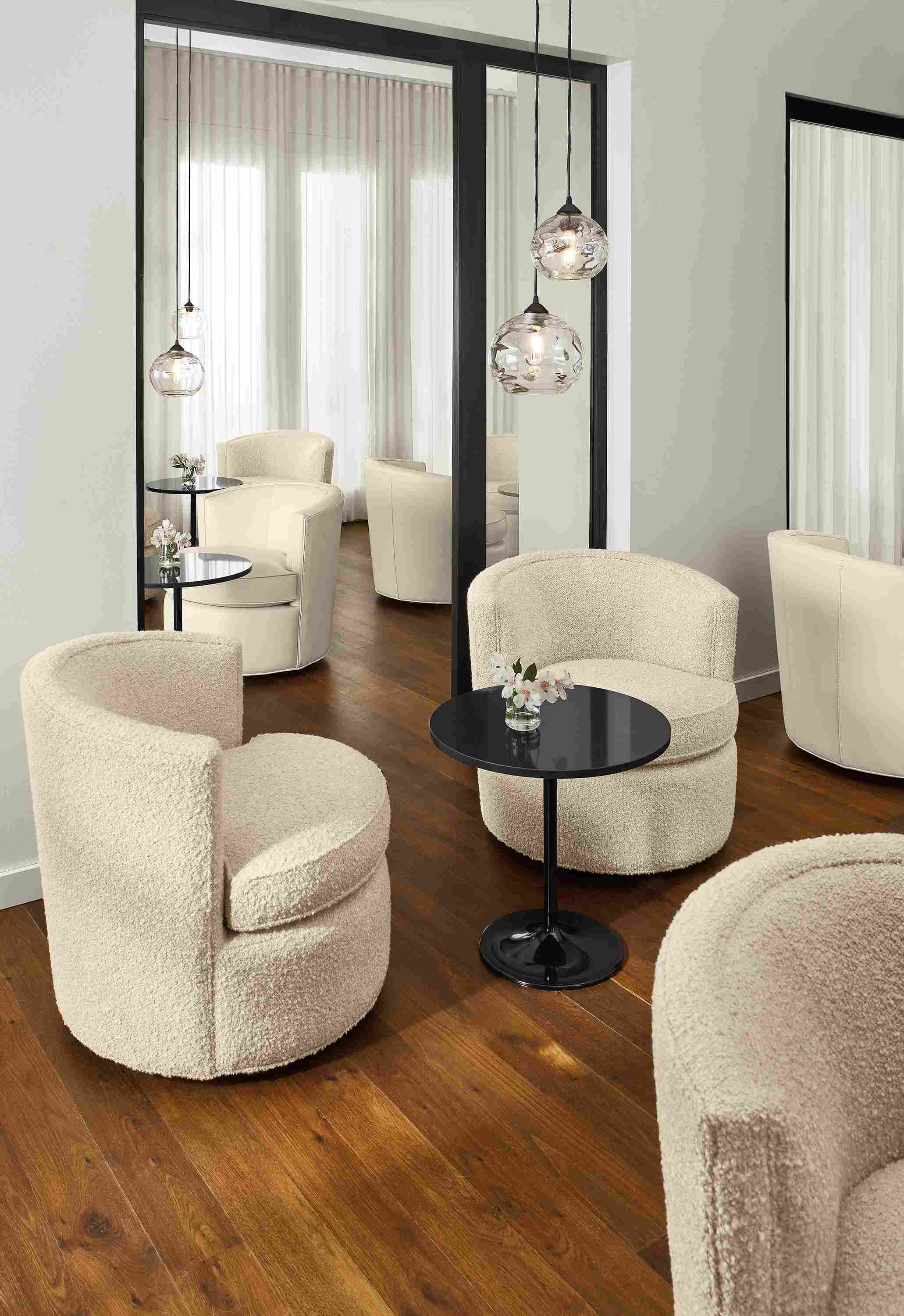 Social setting of multiple Otis swivel chairs in ivory leather and fabric and Aria end tables.