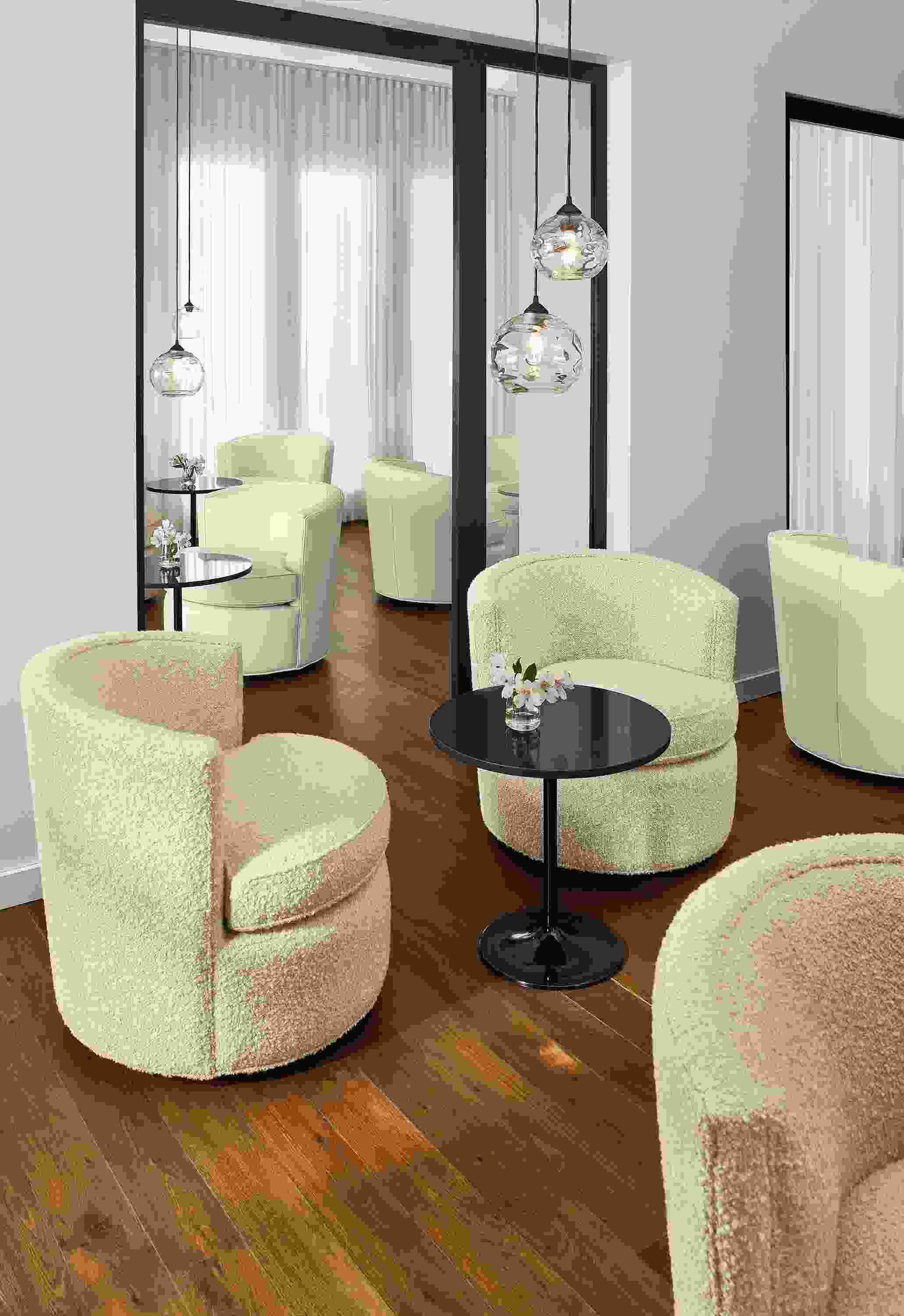 Social setting of multiple Otis swivel chairs in ivory leather and fabric and Aria end tables.