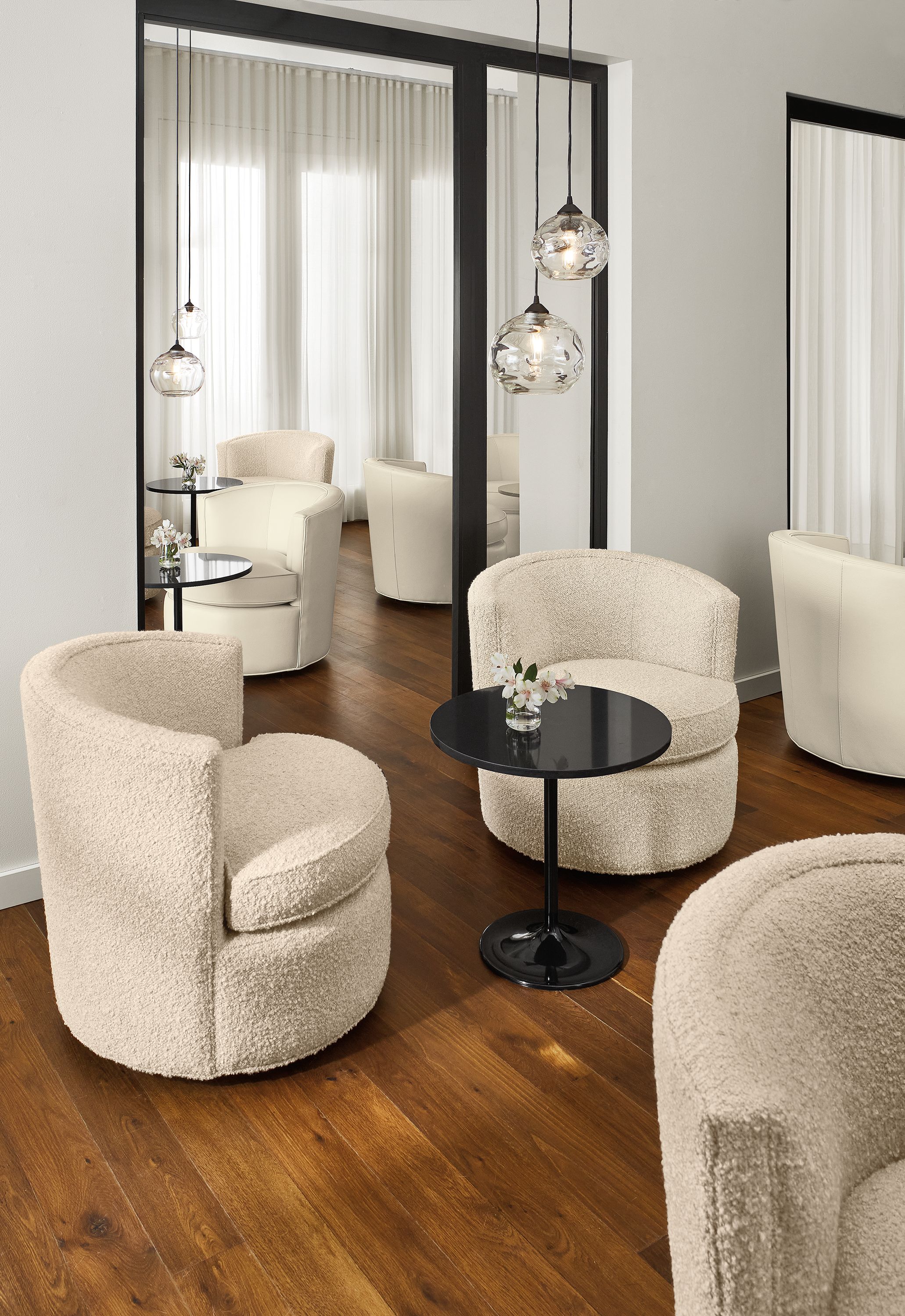 Social setting of multiple Otis swivel chairs in ivory leather and fabric and Aria end tables.