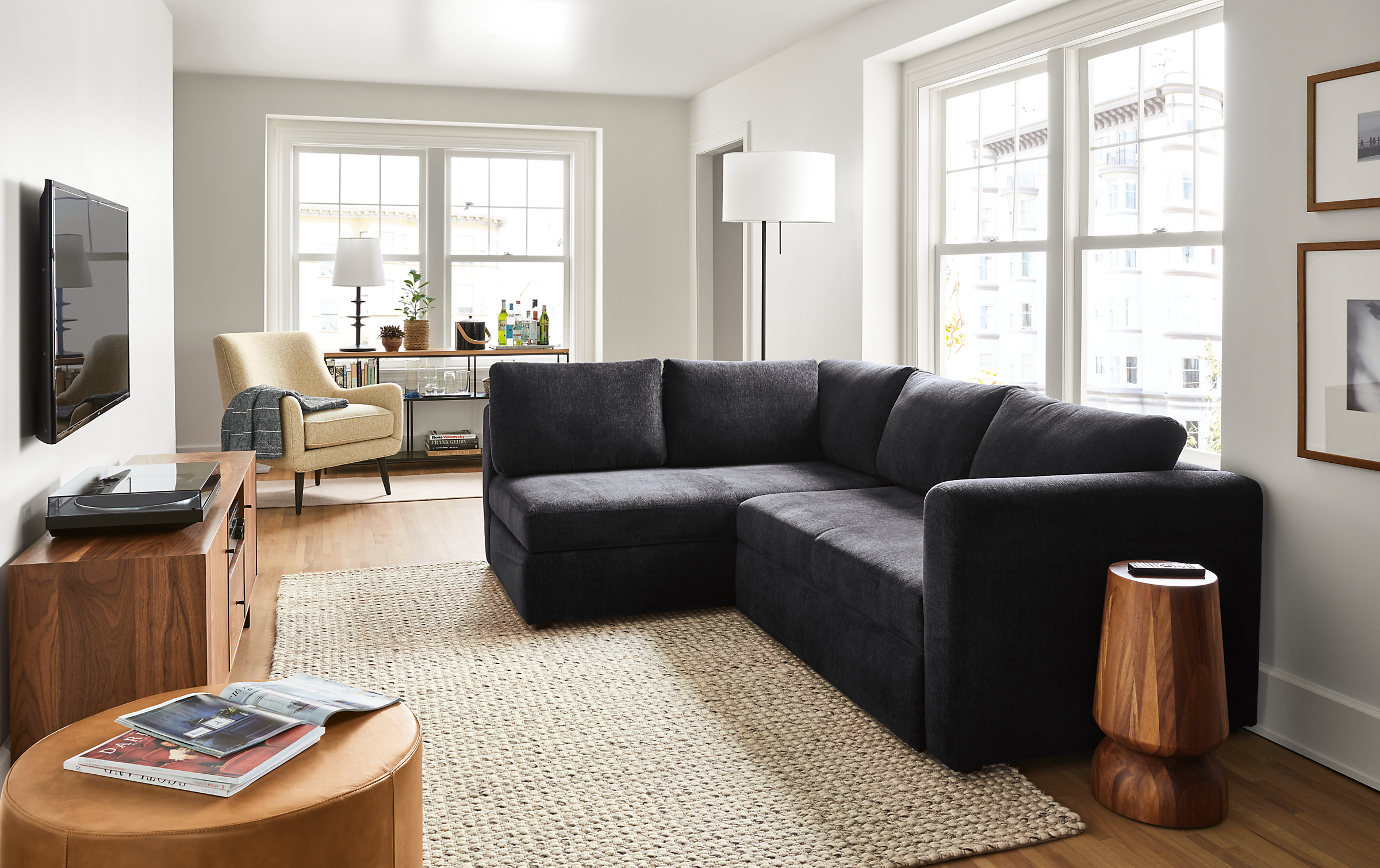 Living room setting with an Oxford Pop-Up Platform Sleeper and a Quinn Chair with an Aero Round Ottoman in leather.
