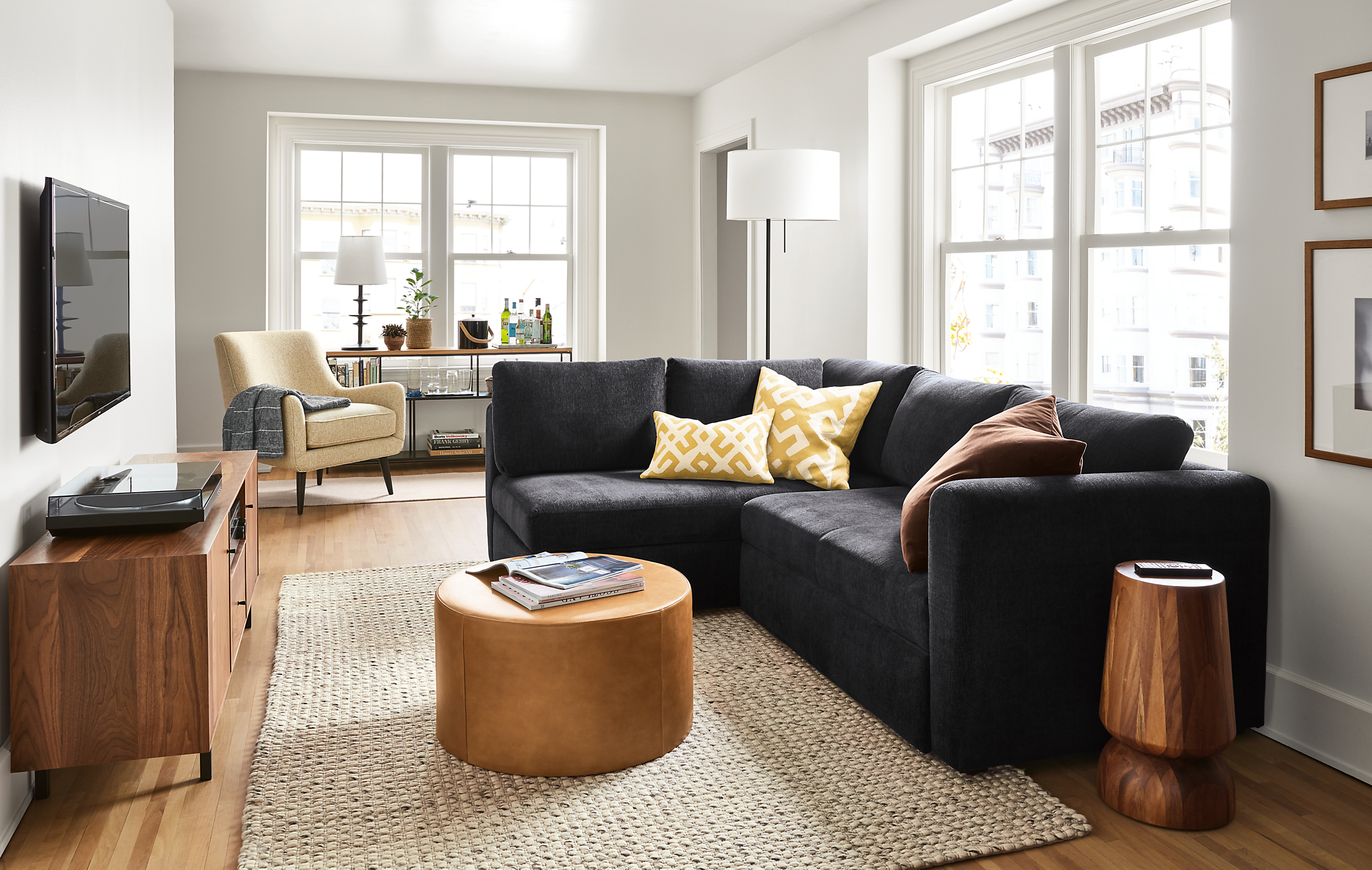 Living room setting with an Oxford Pop-Up Platform Sleeper and a Quinn Chair with an Aero Round Ottoman in leather.