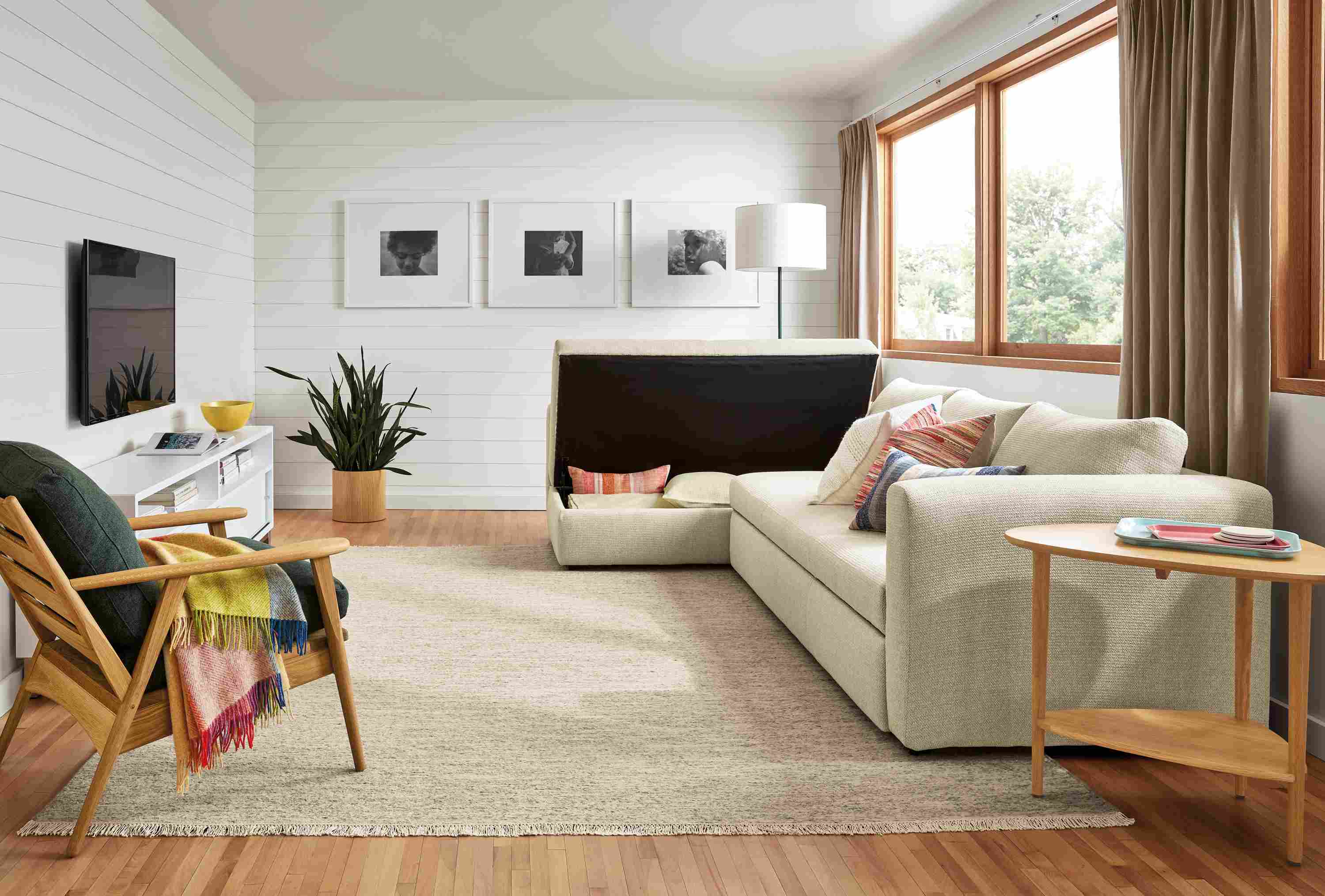 Living room with oxford sleeper sofa in Orla Ivory with storage compartment opened.