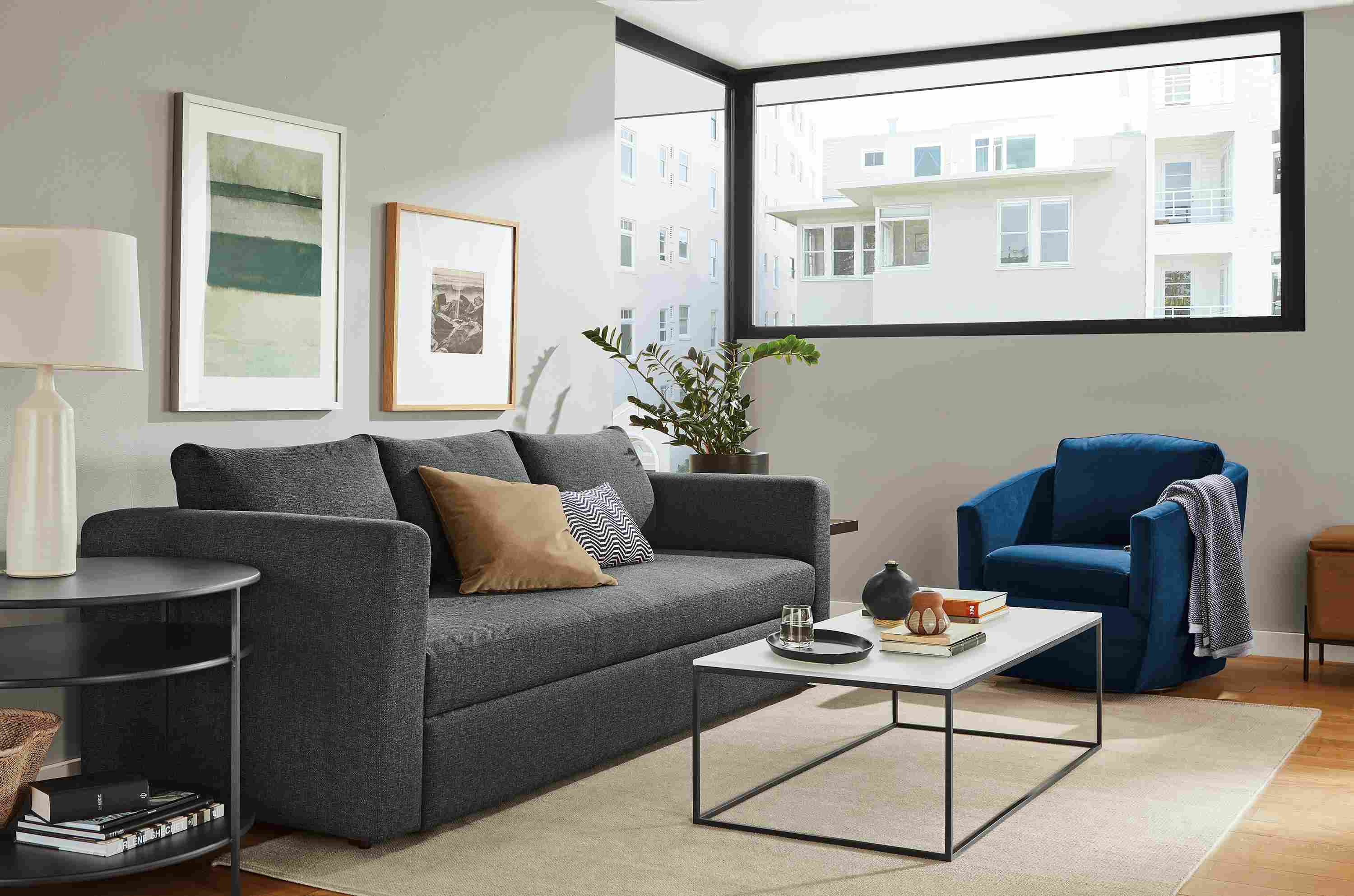 Living room with Oxford sleeper sofa, Otis chair in View Indigo and Tyne coffee table in natural steel with satin etched glass top.