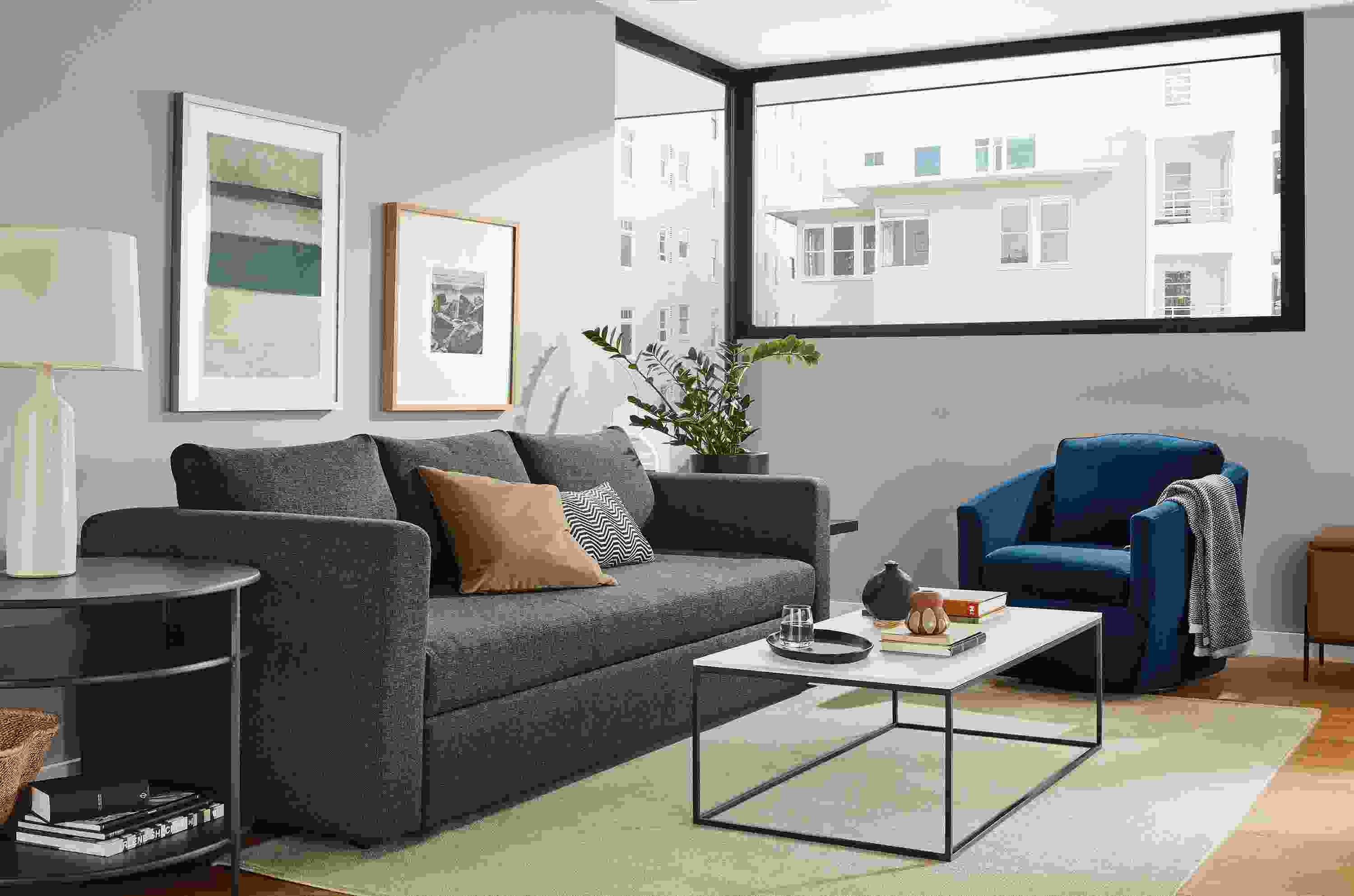 Living room with Oxford sleeper sofa, Otis chair in View Indigo and Tyne coffee table in natural steel with satin etched glass top.