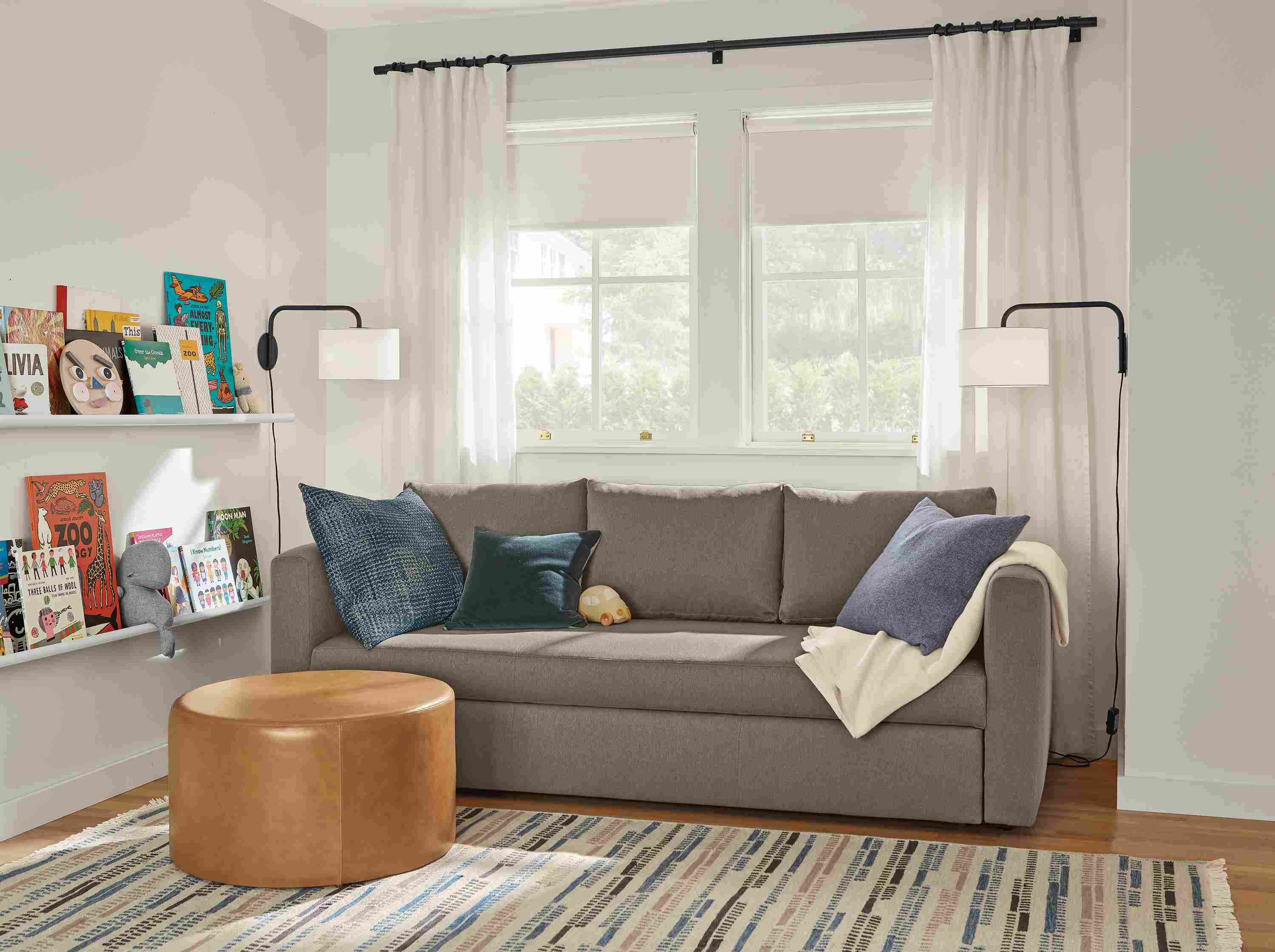 Room setting with an Oxford Pop-Up Platform Full Sleeper Sofa and an 
Aero Round Ottoman in leather.
