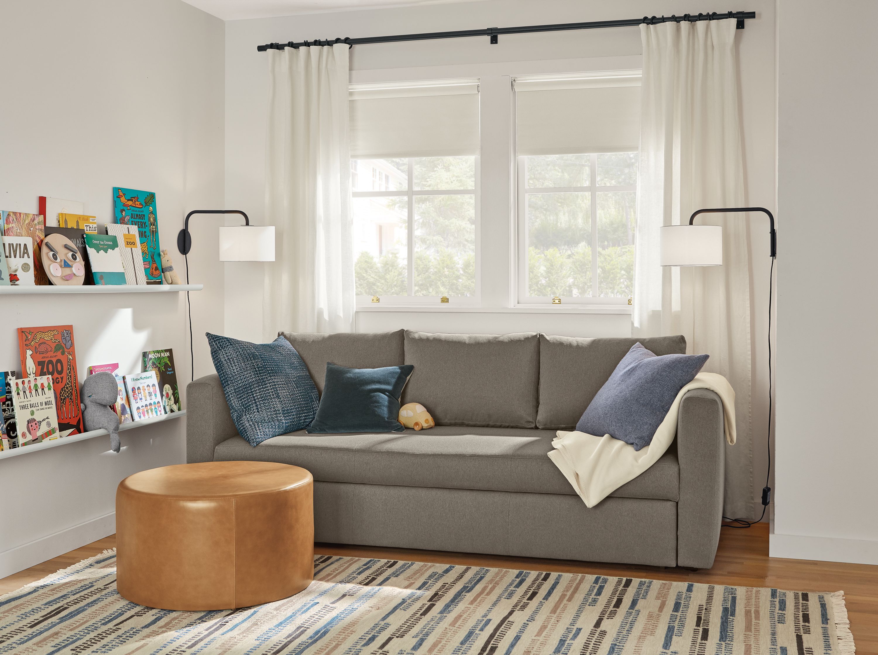 Room setting with an Oxford Pop-Up Platform Full Sleeper Sofa and an 
Aero Round Ottoman in leather.