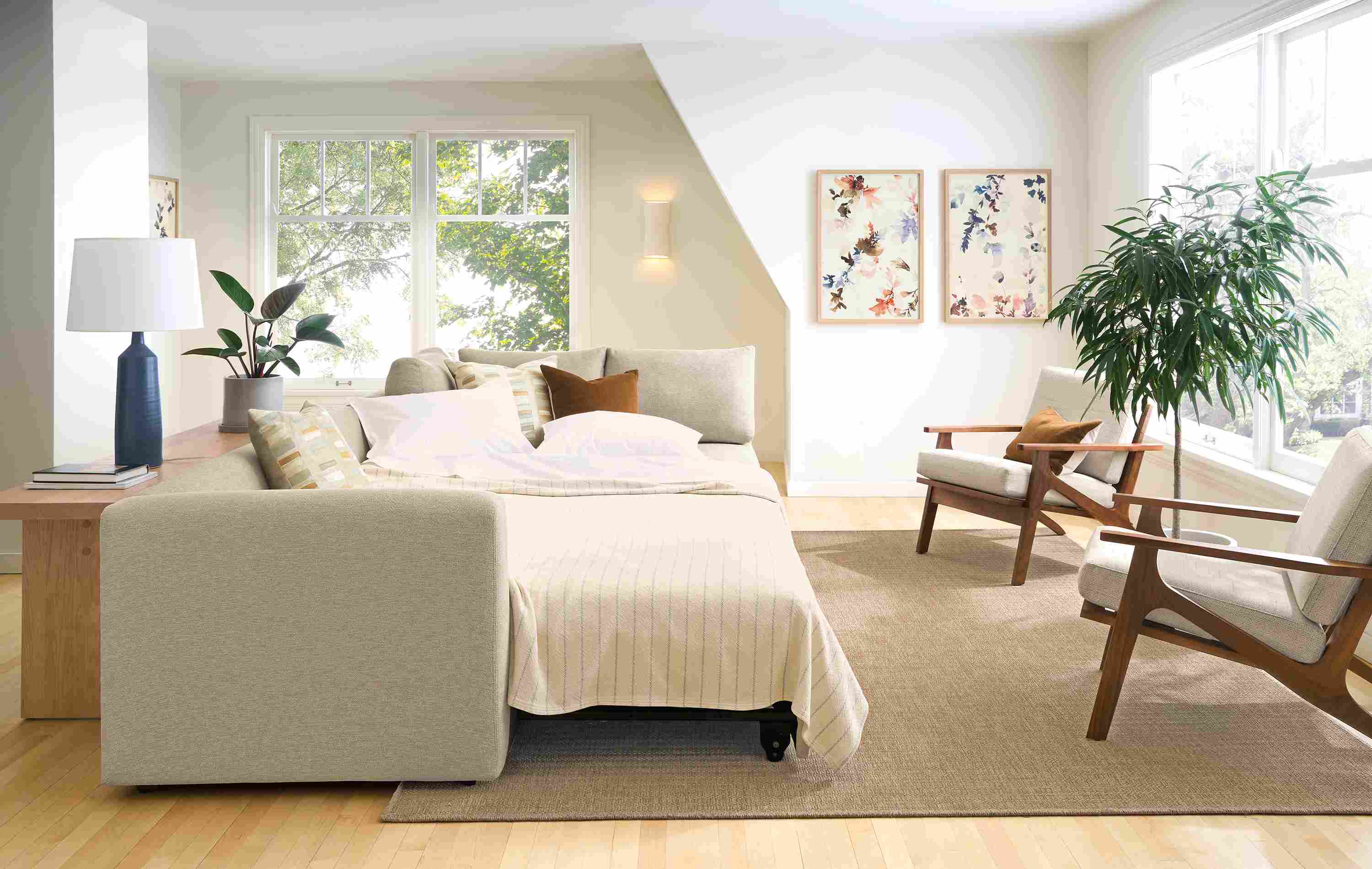 Living room with Oxford track arm 123-wide pop up platform queen sleeper shown with bed extended and a caswell blanket in ivory/grey.