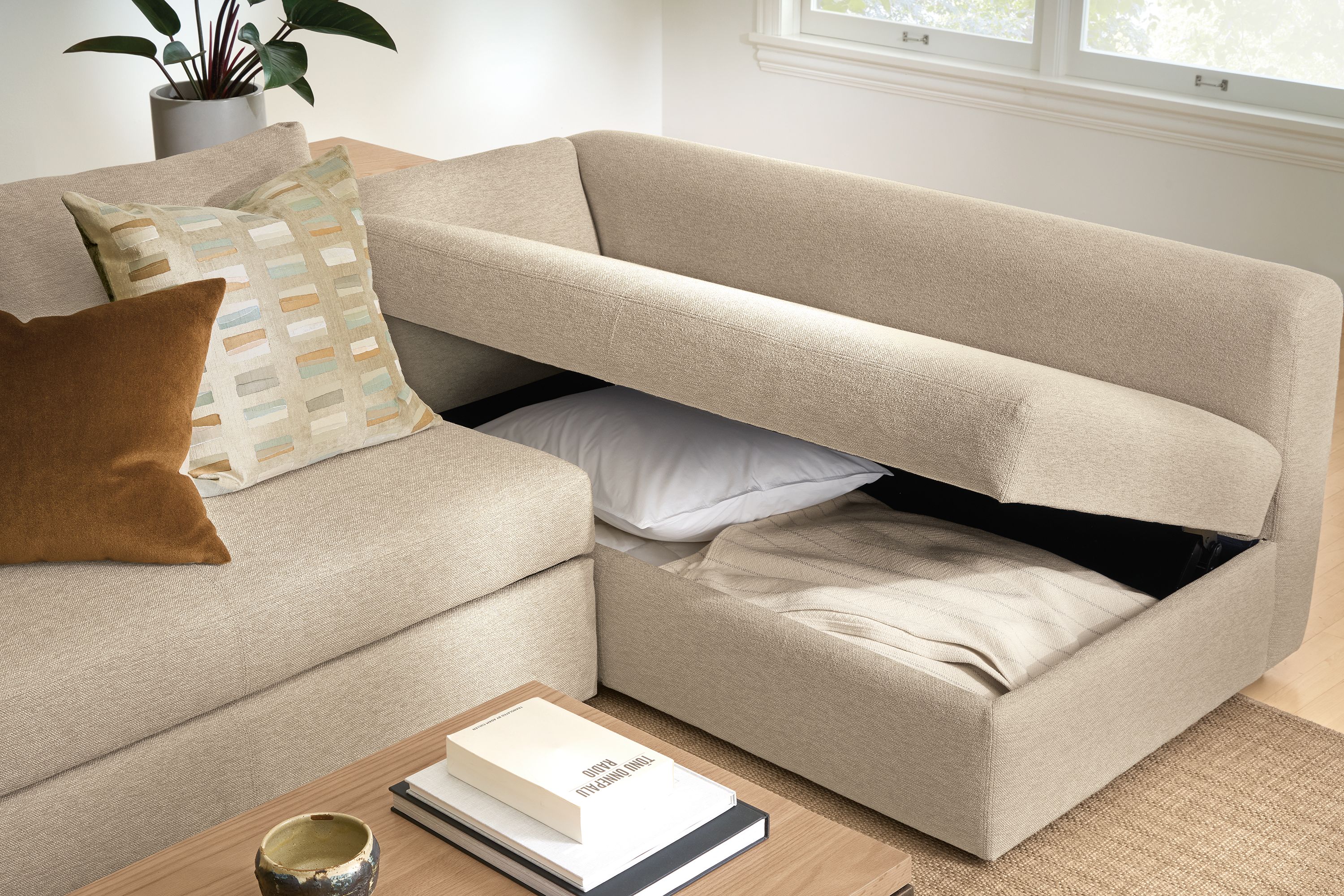 Living room with Oxford track arm 123-wide pop-up platform queen sleeper in Tatum Oatmeal showing open storage compartment.