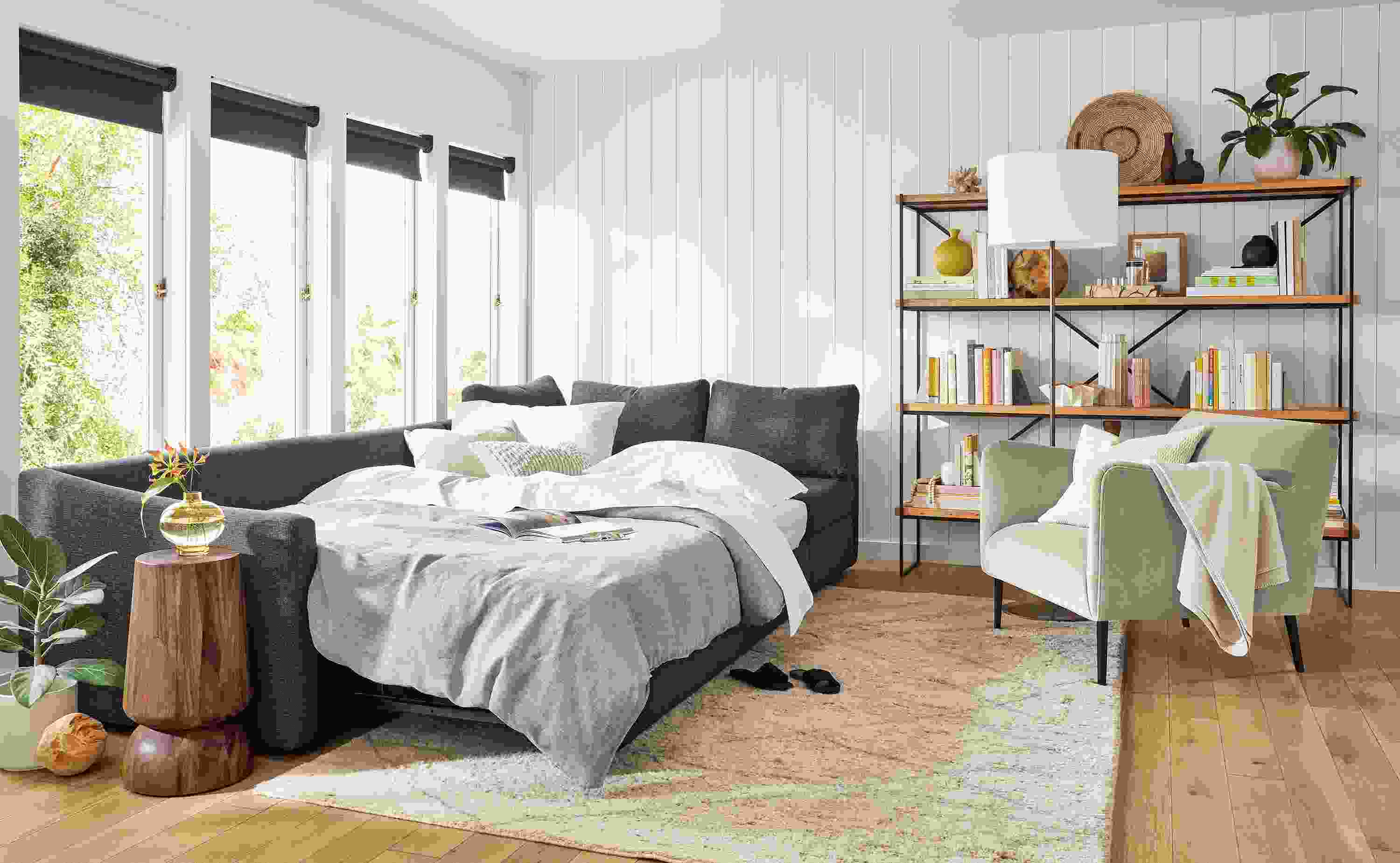 Living area with Oxford pop-up sleeper sectional made into bed, Matteo chair in Vance asphalt and Etting 72-wide bookcase.