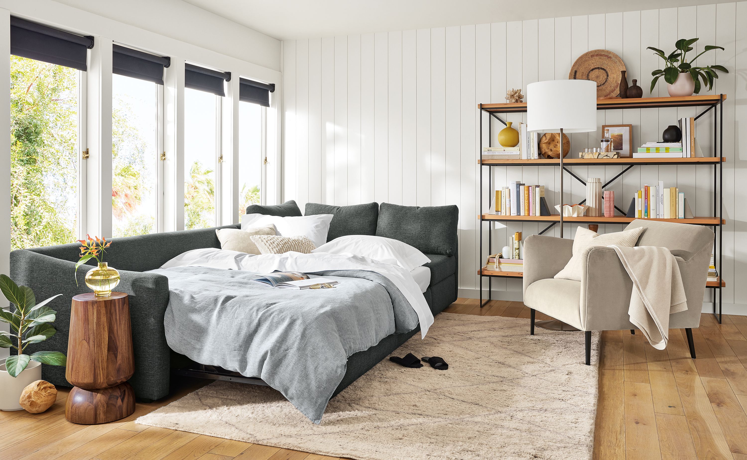 Living area with Oxford pop-up sleeper sectional made into bed, Matteo chair in Vance asphalt and Etting 72-wide bookcase.