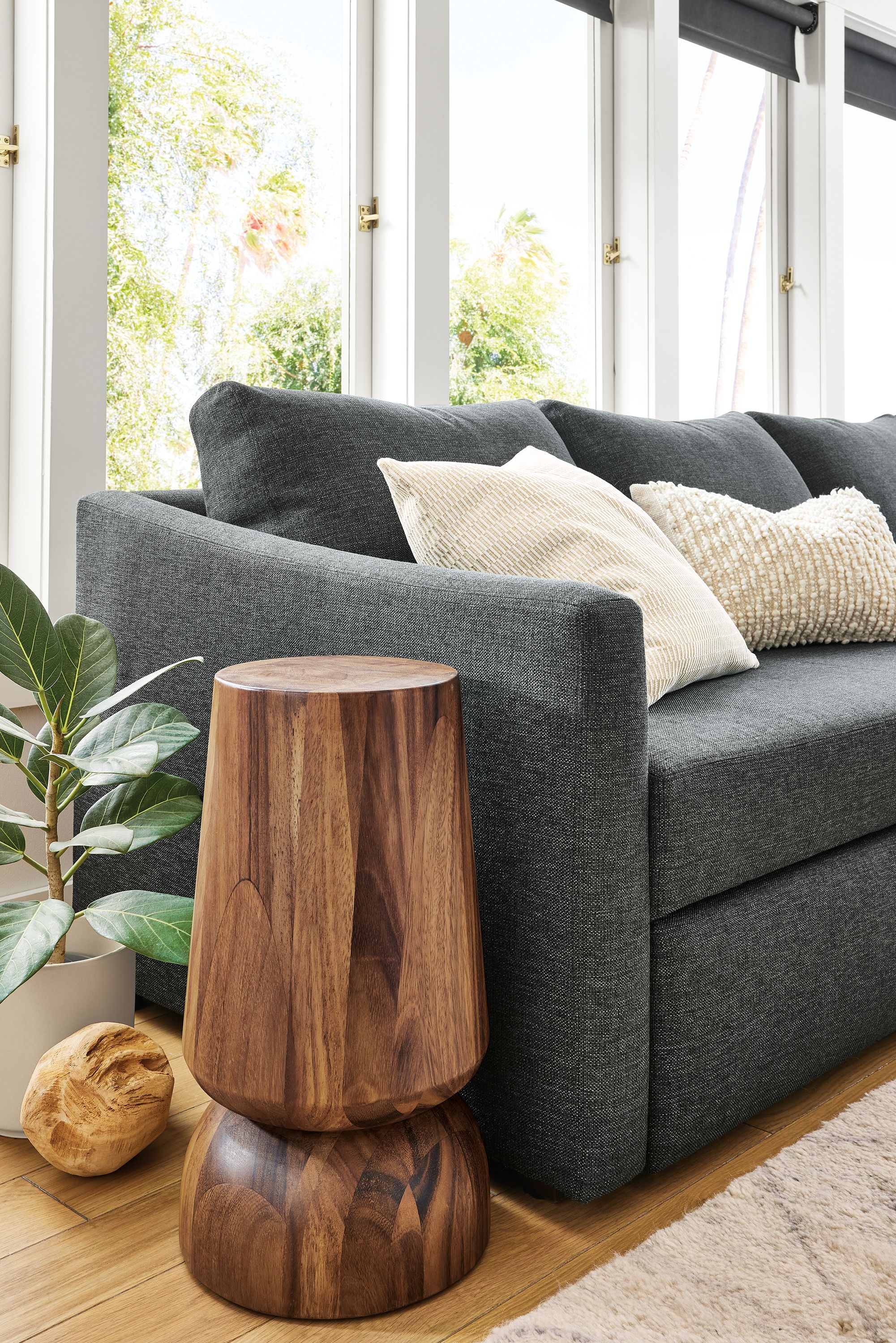 Close up of Oxford Pop-up sleeper sectional with slope arm in Sumner charcoal and Nyla end table in natural solid Conacaste wood.