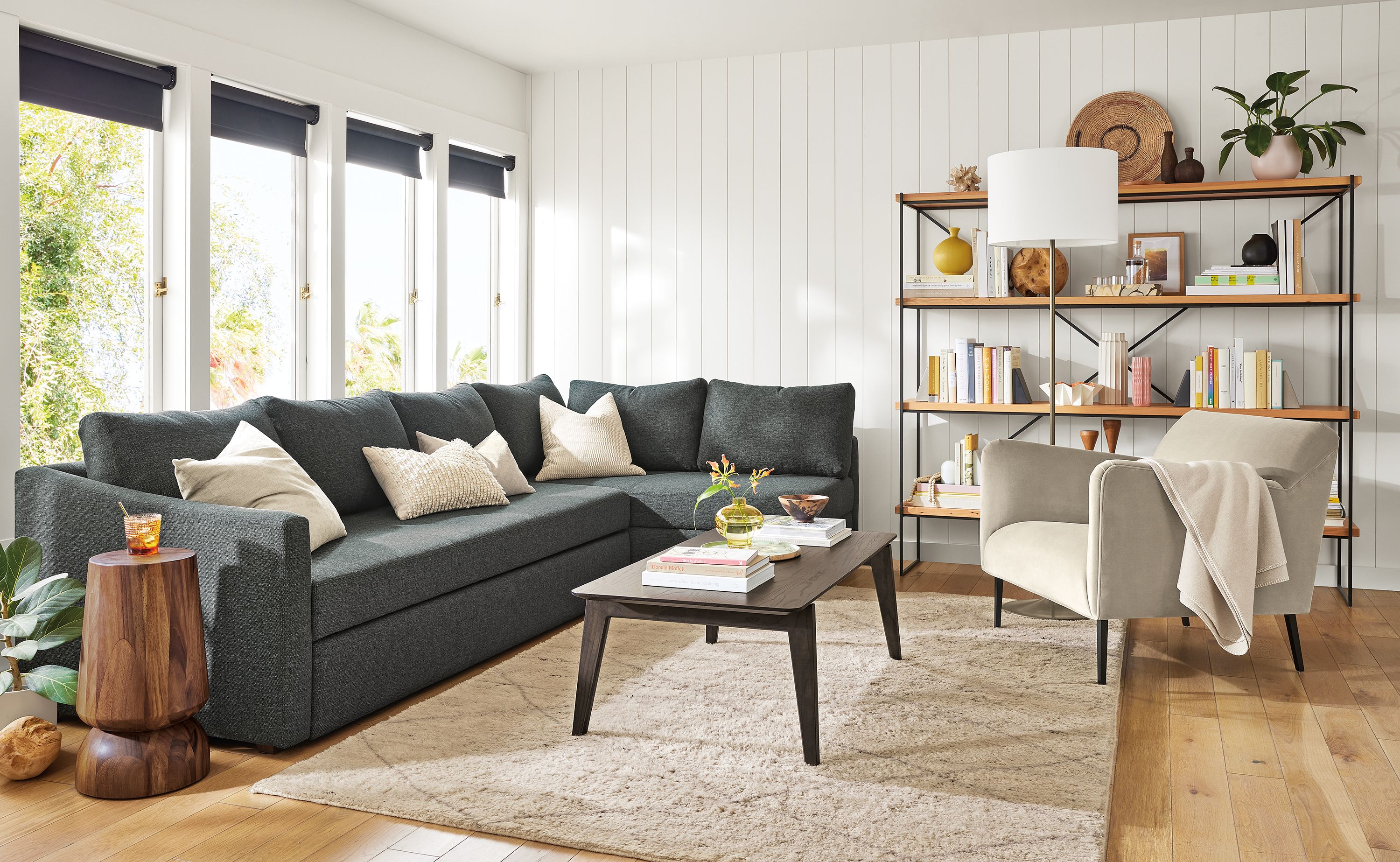 Living area with Oxford pop-up platform sectional in Sumner charcoal, Matteo chair in Vance asphalt and  Orlin coffee table in charcoal.