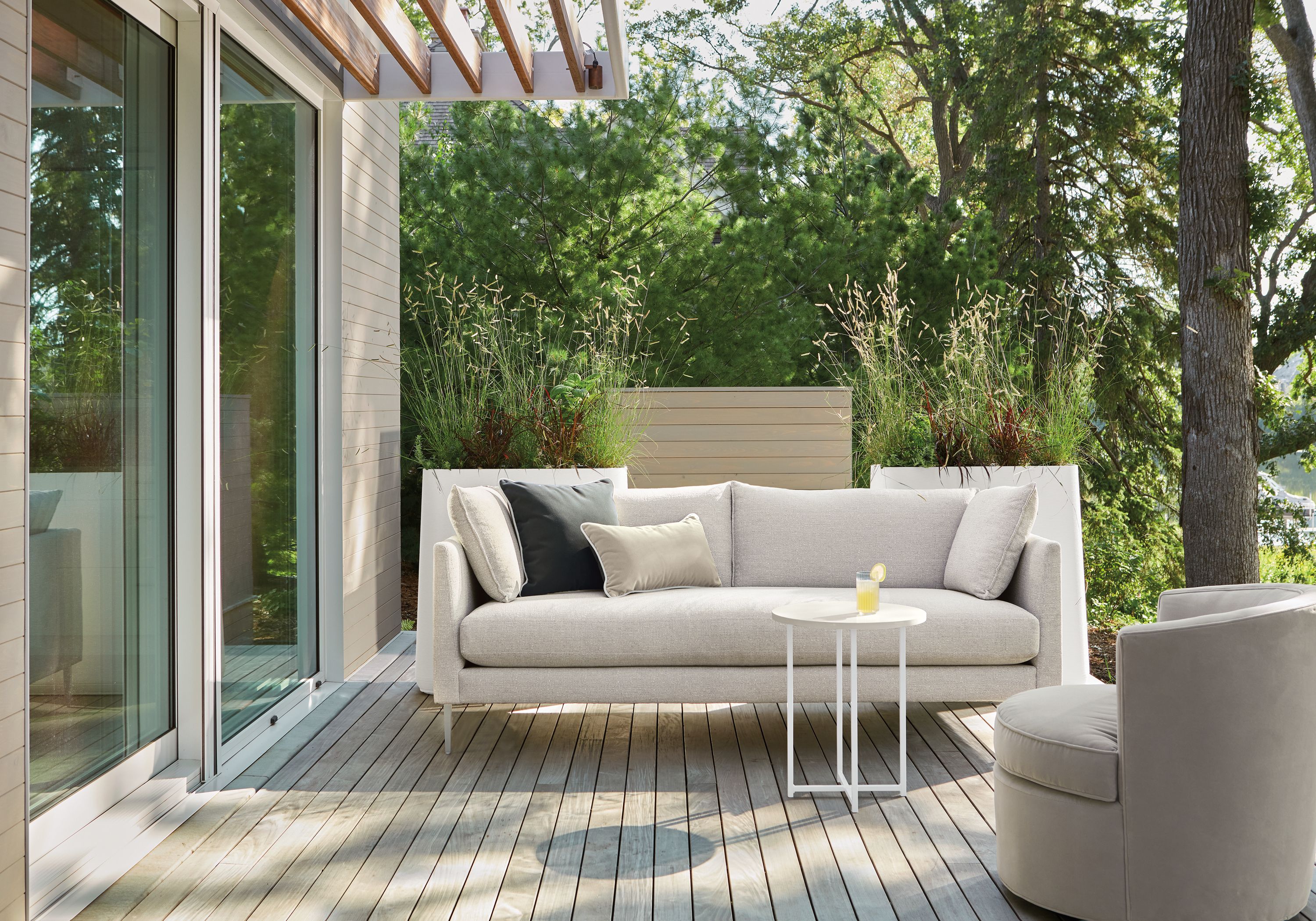 Outdoor space with Palm sofa in Nevan Grey, Ambrose swivel chair in Tristan Putty and Classic round table in white.
