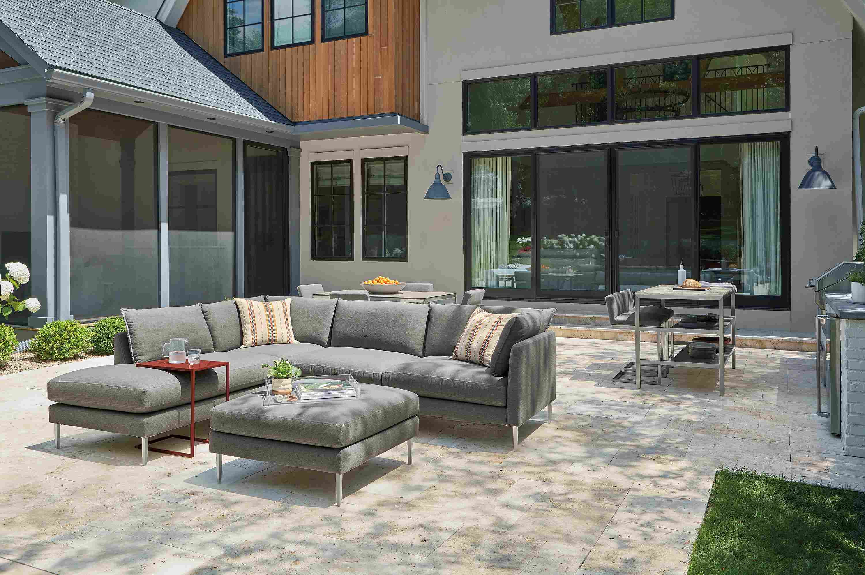 Palm sectional and ottoman in Pelham grey, Parsons 60-wide outdoor counter with two narrow shelves and Finn counter stools.