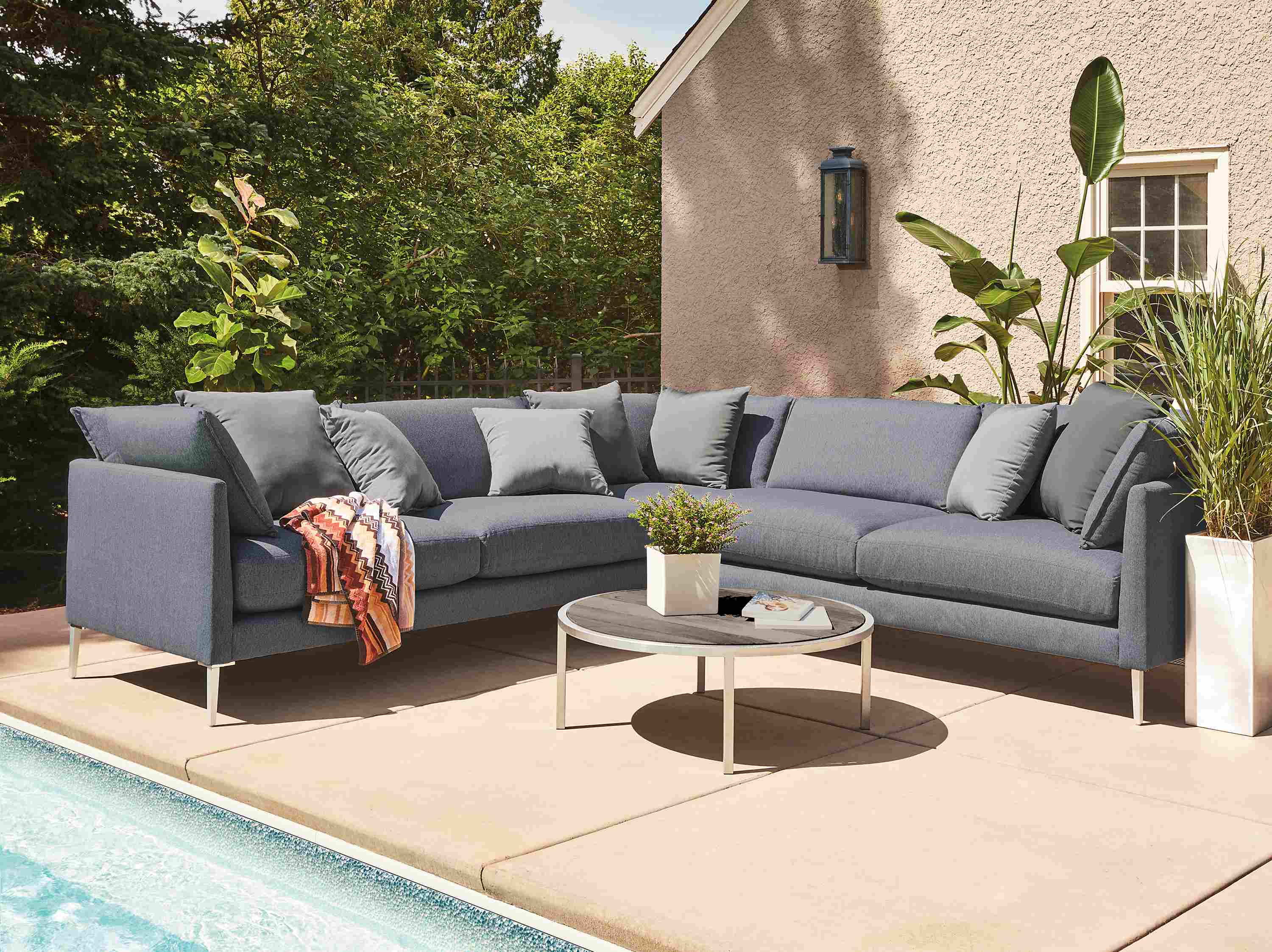 Poolside area with Palm sectional sofa in Mist navy and Montego table in aged thermally modified oak.