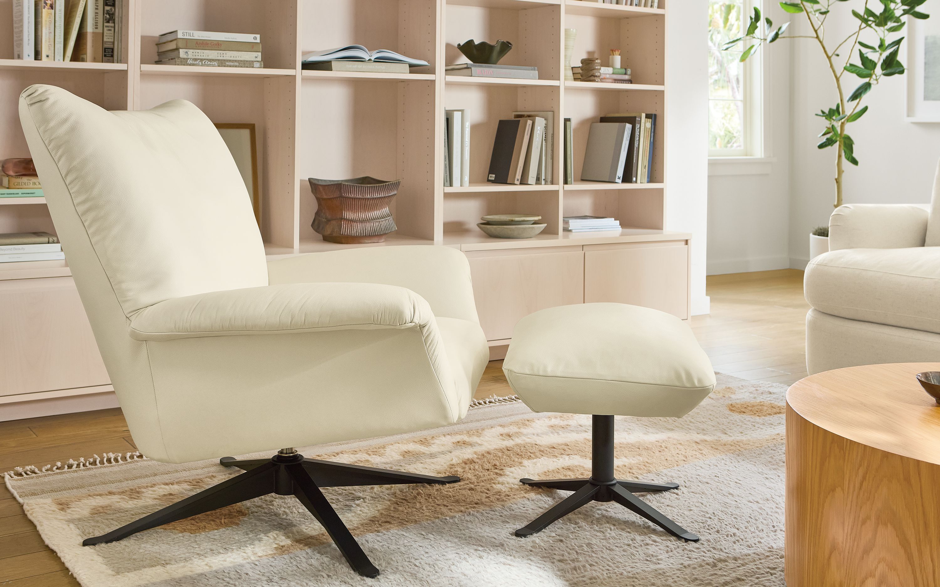 Living room with Paris swivel chair and ottoman in pesaro ivory and tova rug in sand.