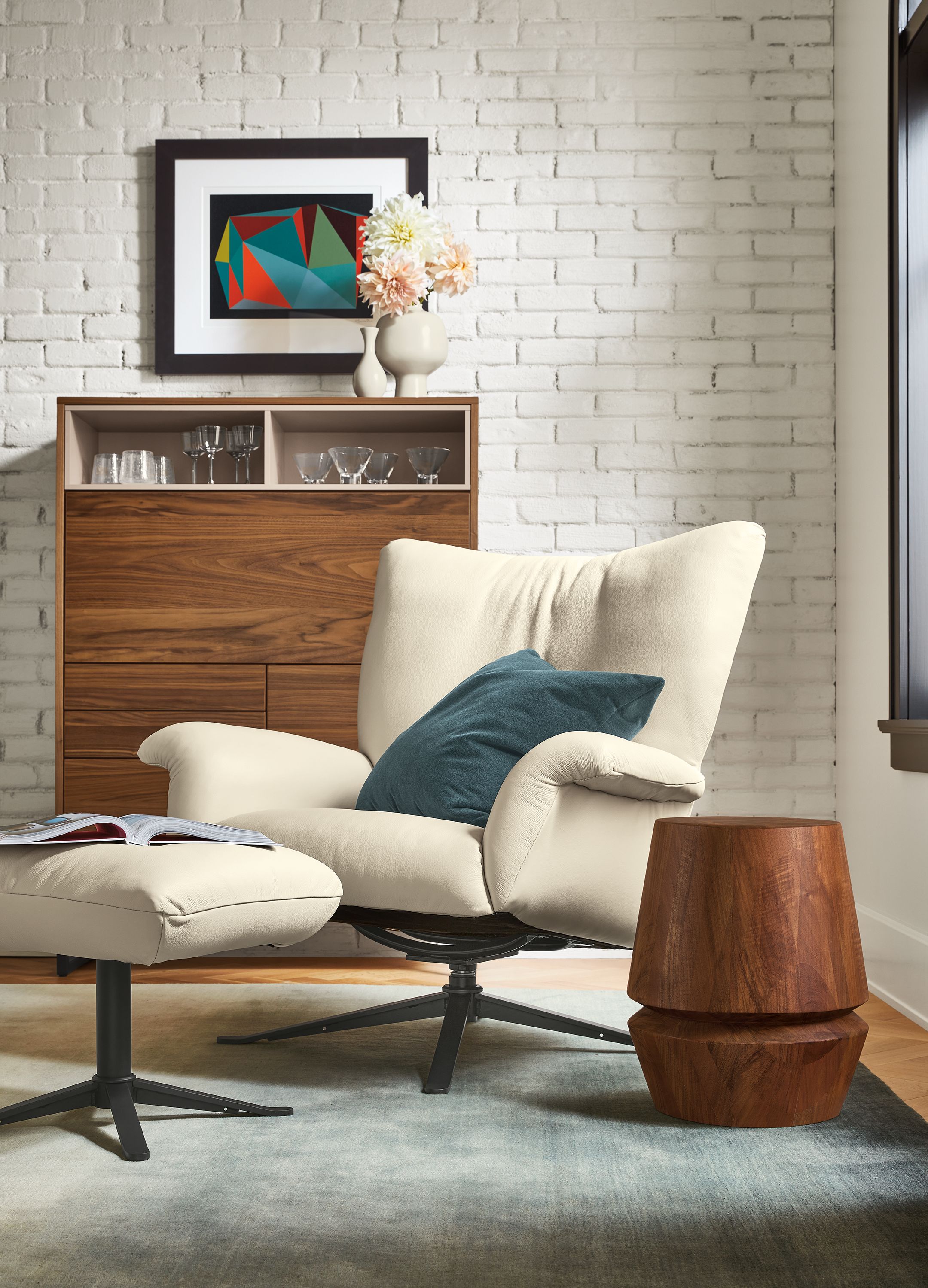 Living area with Paris swivel chair and ottoman in Pesaro Ivory leather and Mosby Armoire in Walnut.