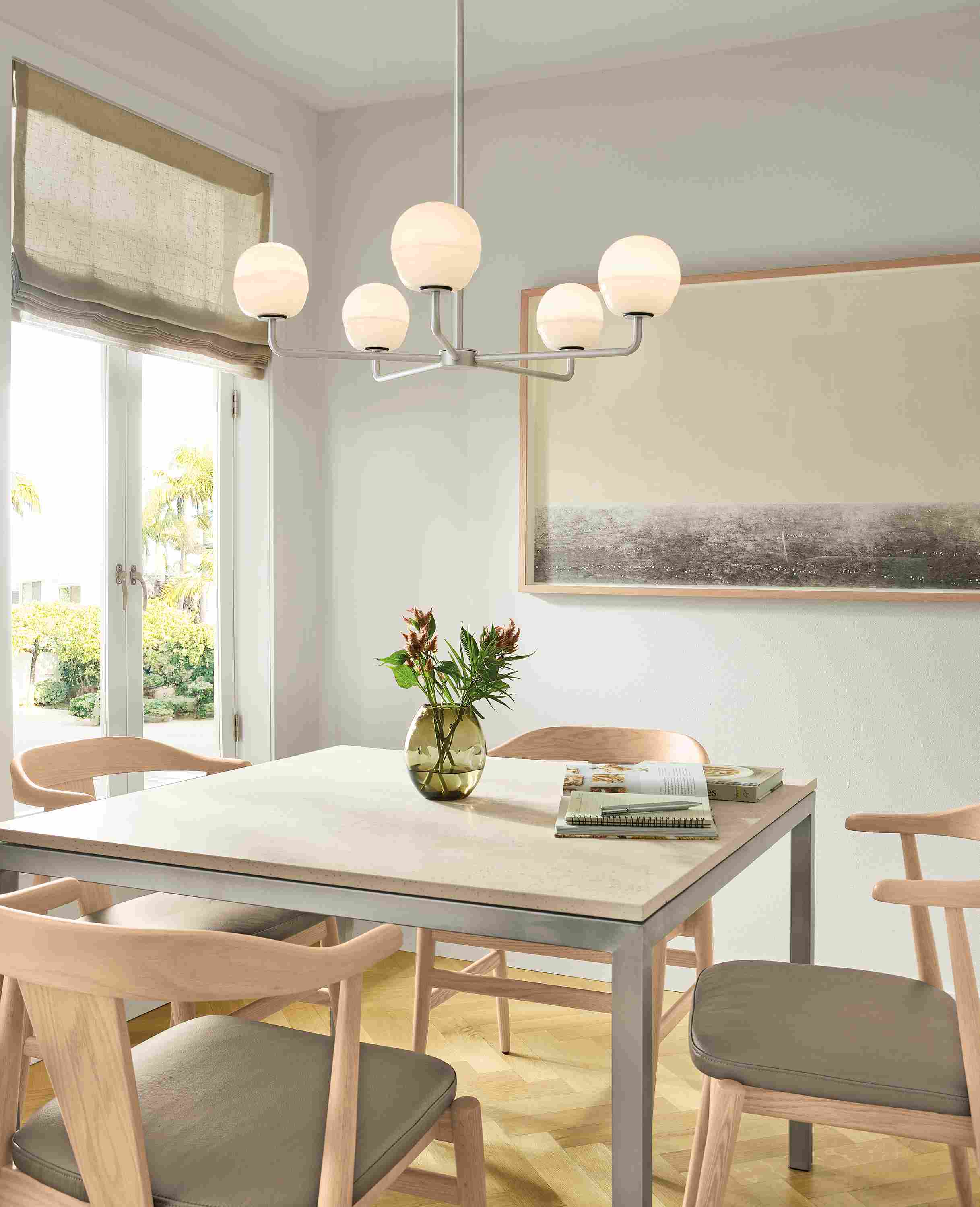Dining area with Parson table in marbled beige stone and stainless and 4 Evan arm chairs in Pesaro Putty leather.