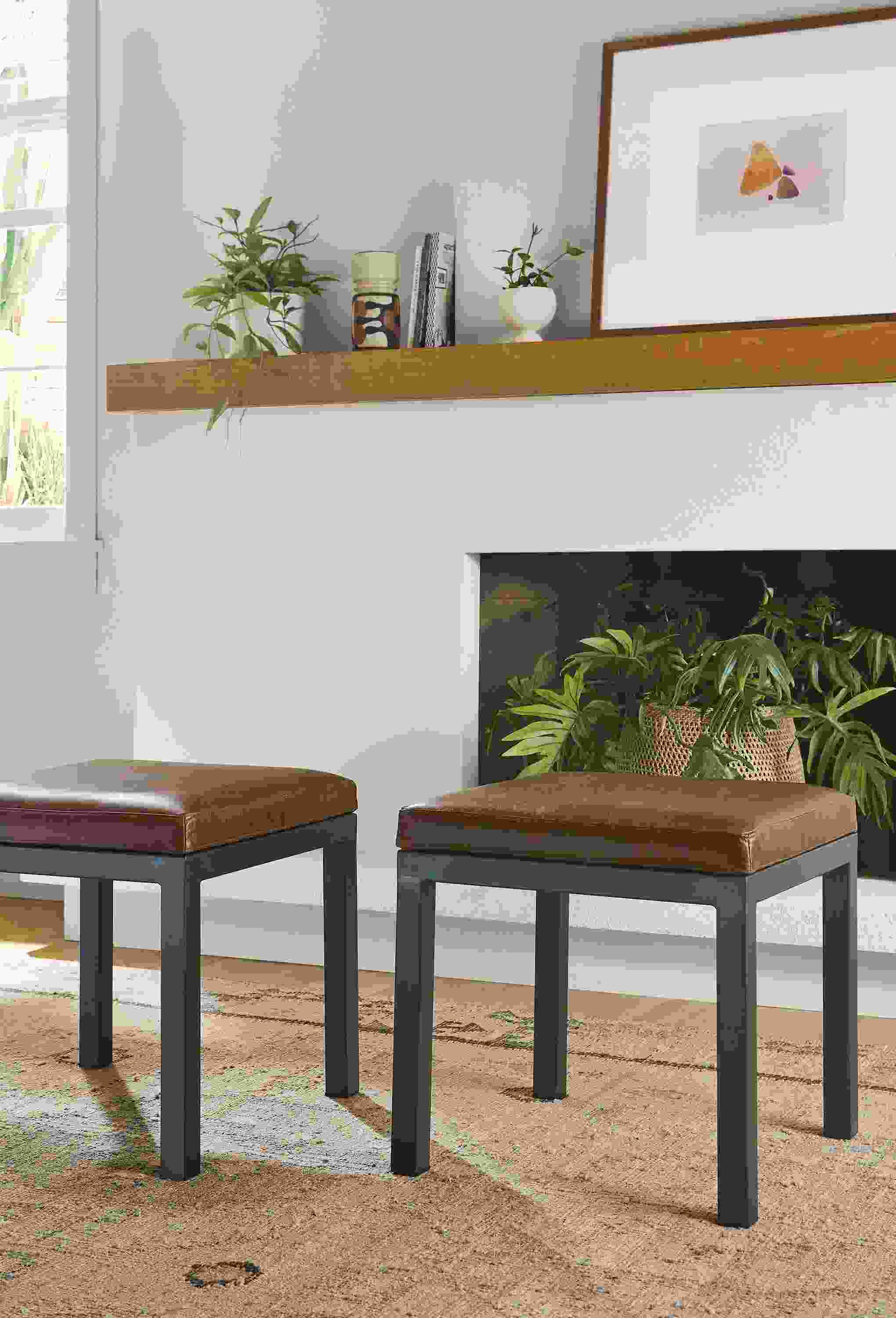 Living room with 2 Parsons 18 by 18 Benches in Palermo Bourbon leather, Villa rug in sand and Julius Bissier artwork.