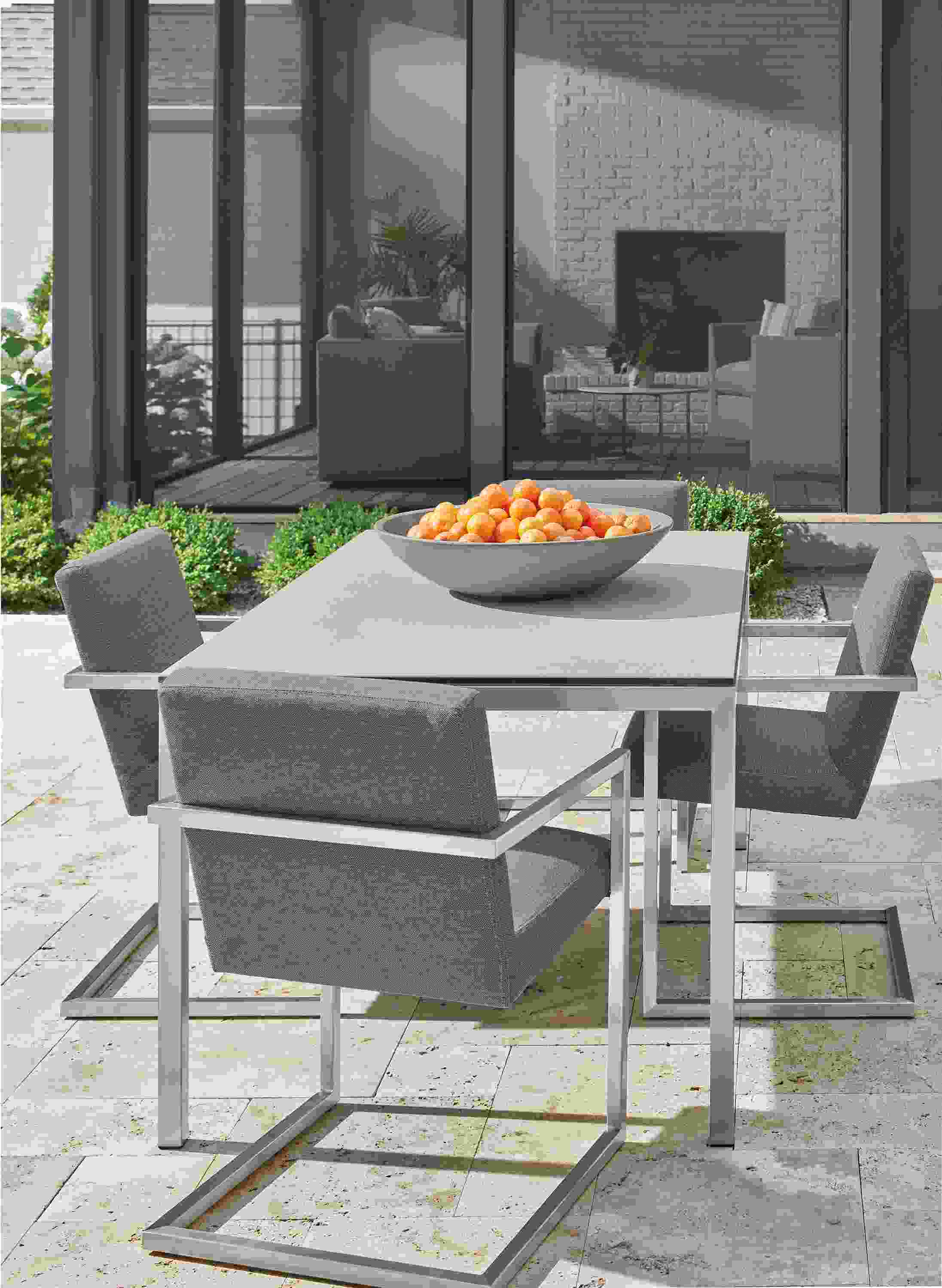 Parsons outdoor table in stainless steel with taupe ceramic top and 4 Finn arm chairs in Pelham grey fabric.