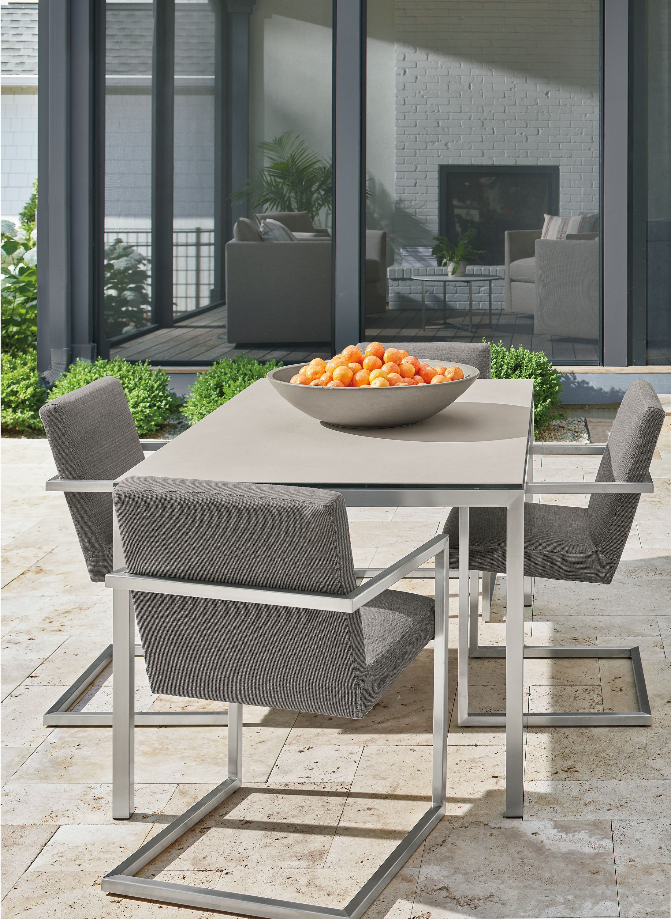 Parsons outdoor table in stainless steel with taupe ceramic top and four Finn arm chairs in Pelham grey fabric.