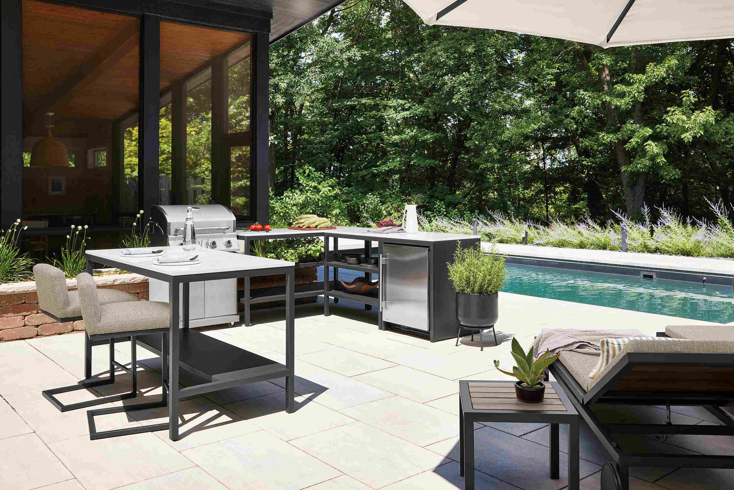Outdoor space with parsons modular outdoor kitchen with fridge in graphite and marbled white quartz.
