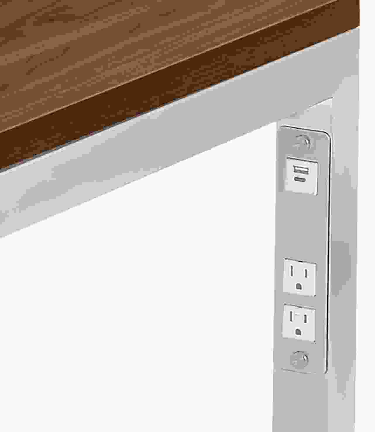 Detail of Parsons desk  in stainless steel with usb and  power cord outlets.