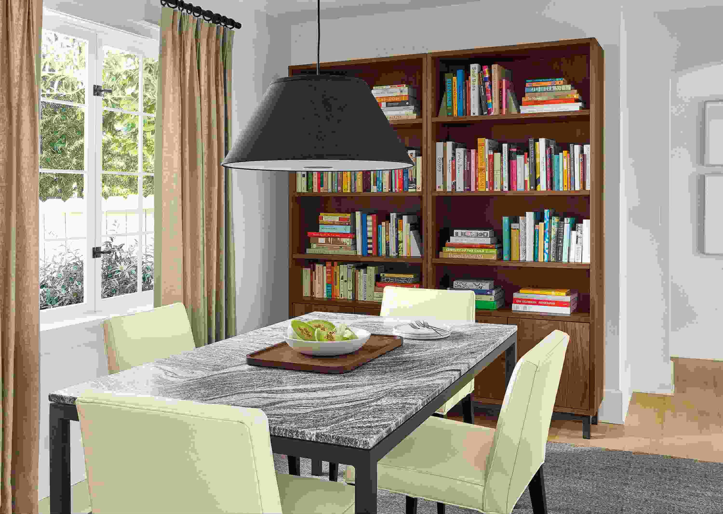 Dining room with Parsons table in natural steel and Wiscont White Granite, Ava chairs, Luisa pendant, Copenhagen bookcases.