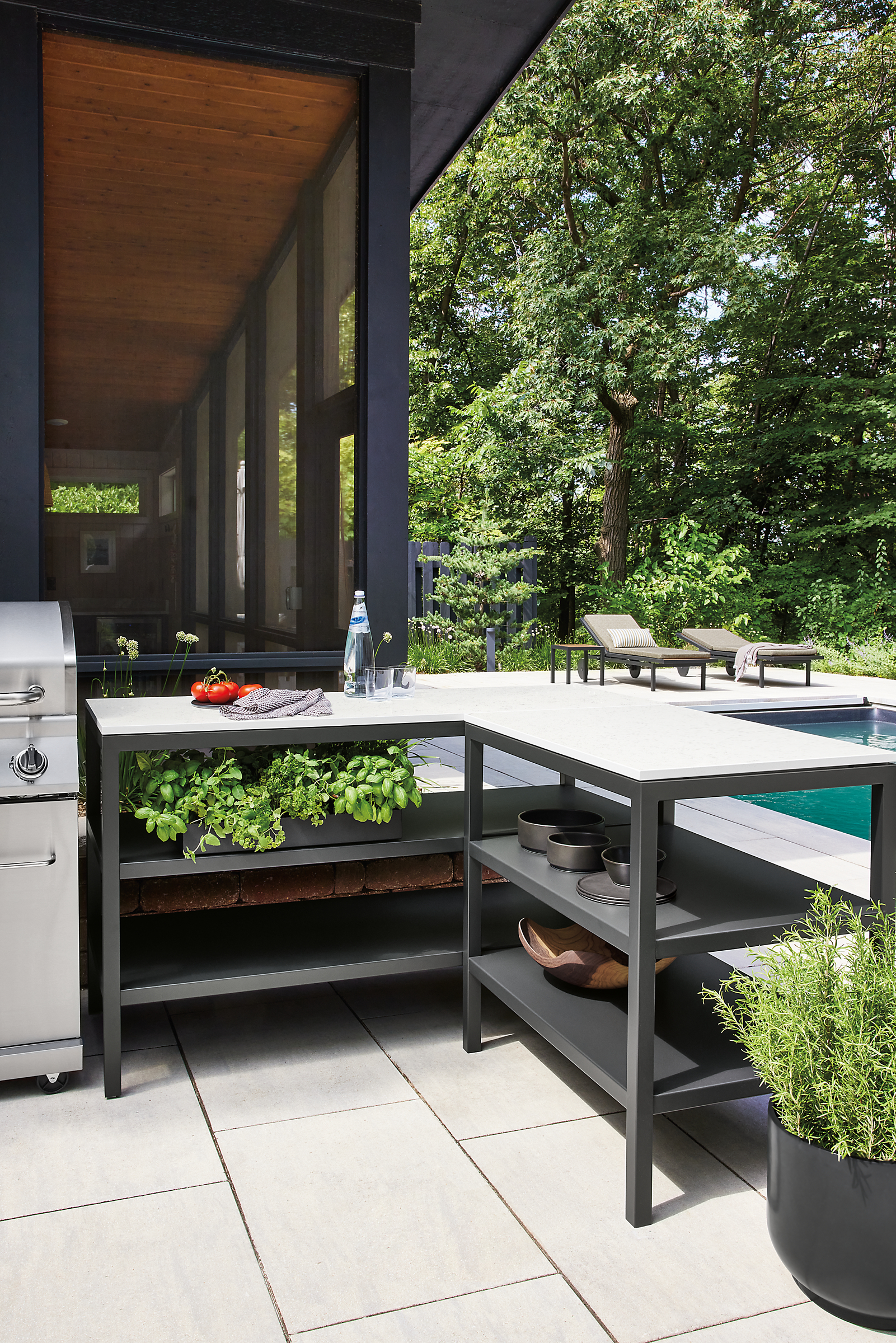 Outdoor space with parsons counter L-shaped table and lots of basil on one shelf.