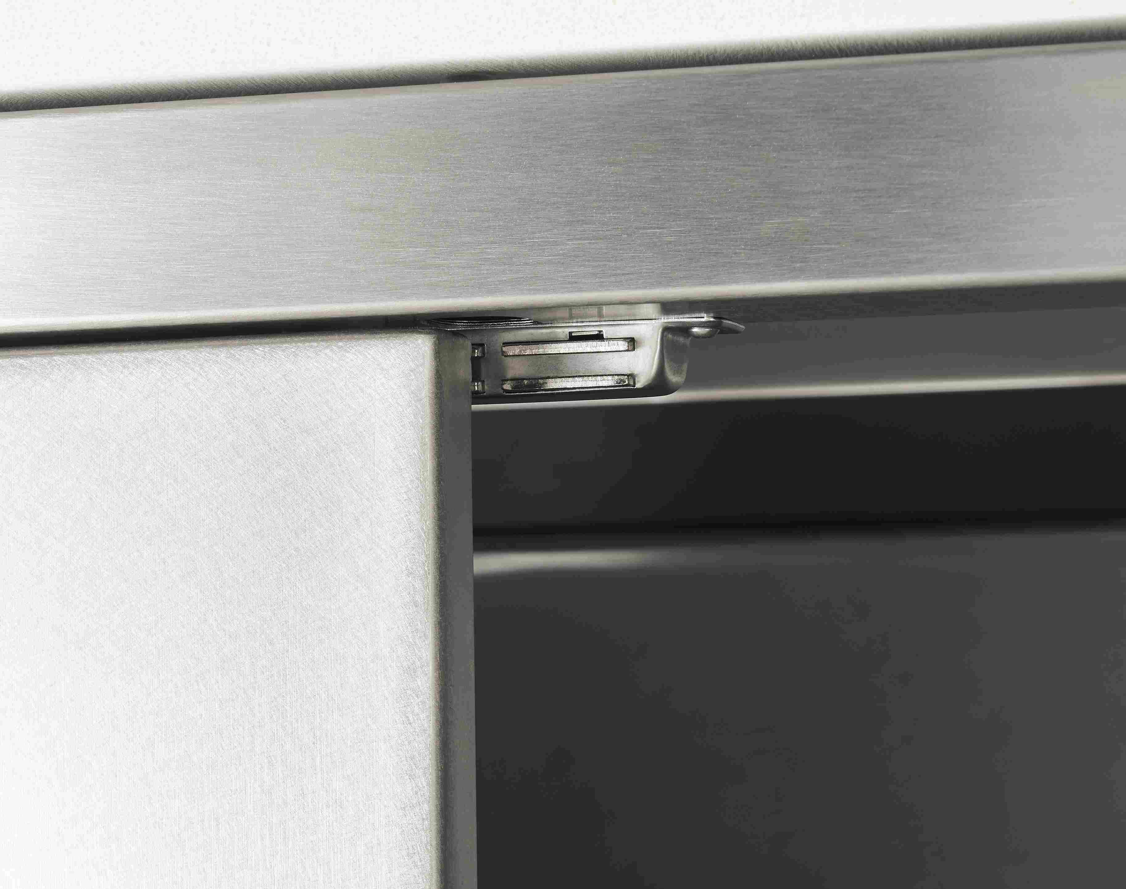 Detail of door magnet on parsons outdoor kitchen storage cabinet in stainless steel.