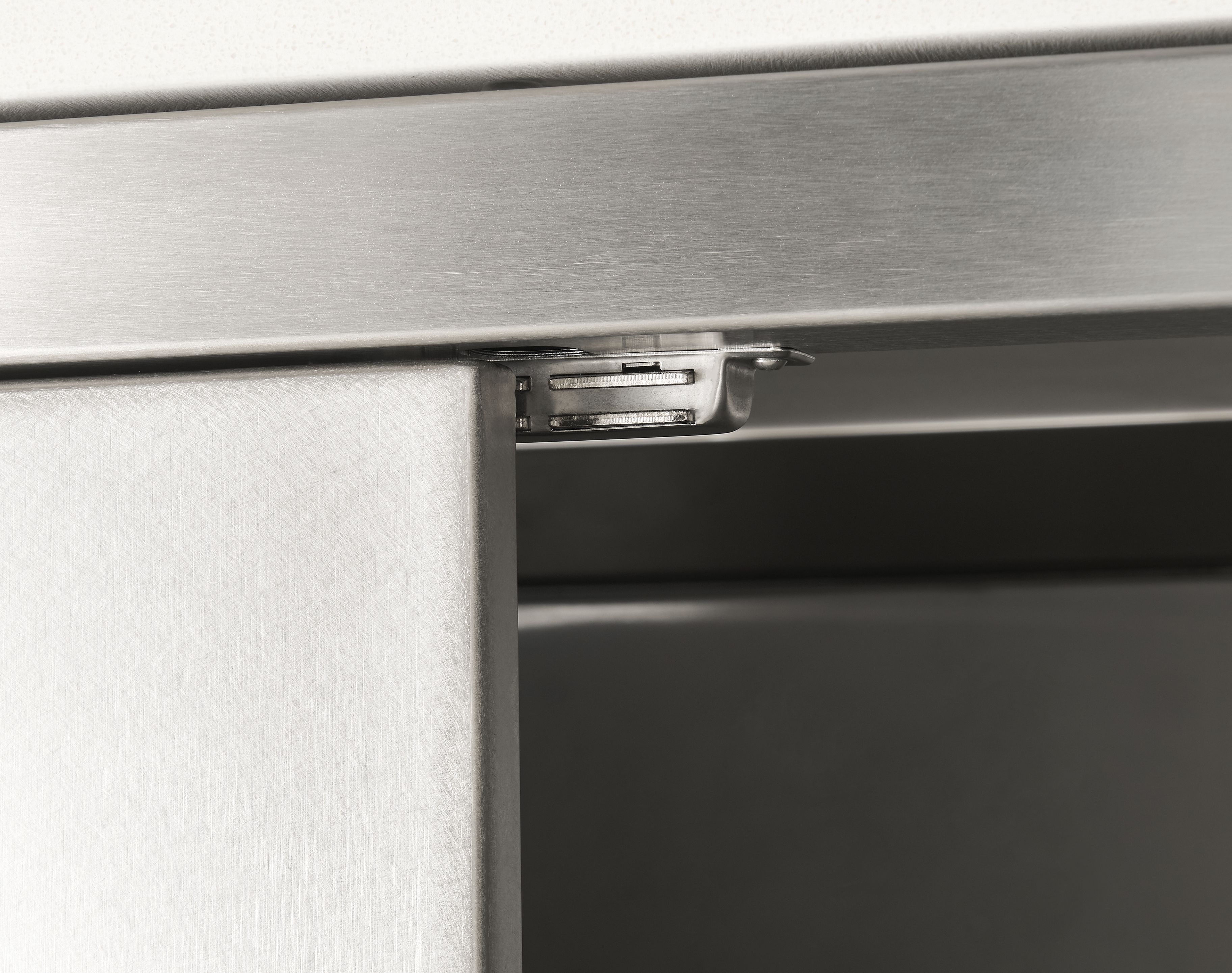 Detail of door magnet on parsons outdoor kitchen storage cabinet in stainless steel.