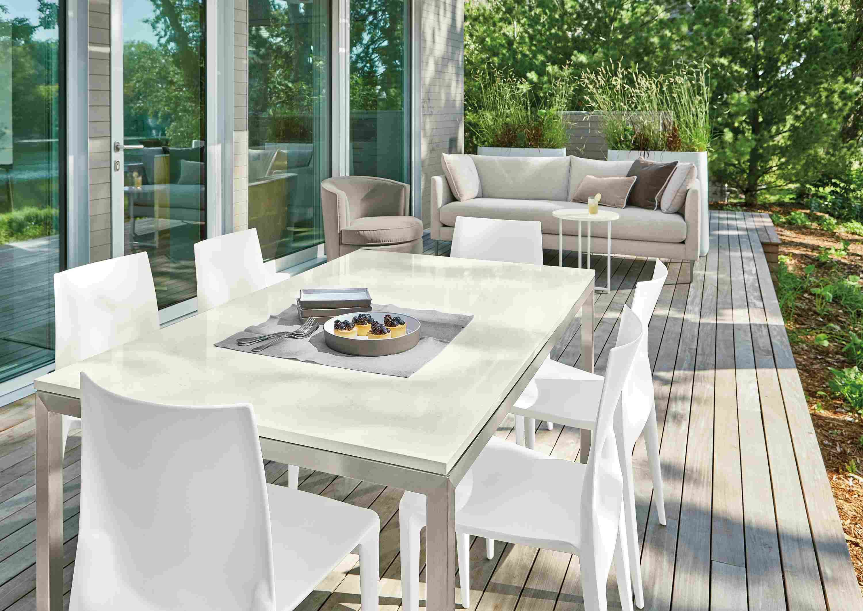 Outdoor space with Parsons table in stainless steel with quartz top, Bellini chairs in white, Palm sofa, Ambrose swivel chair.
