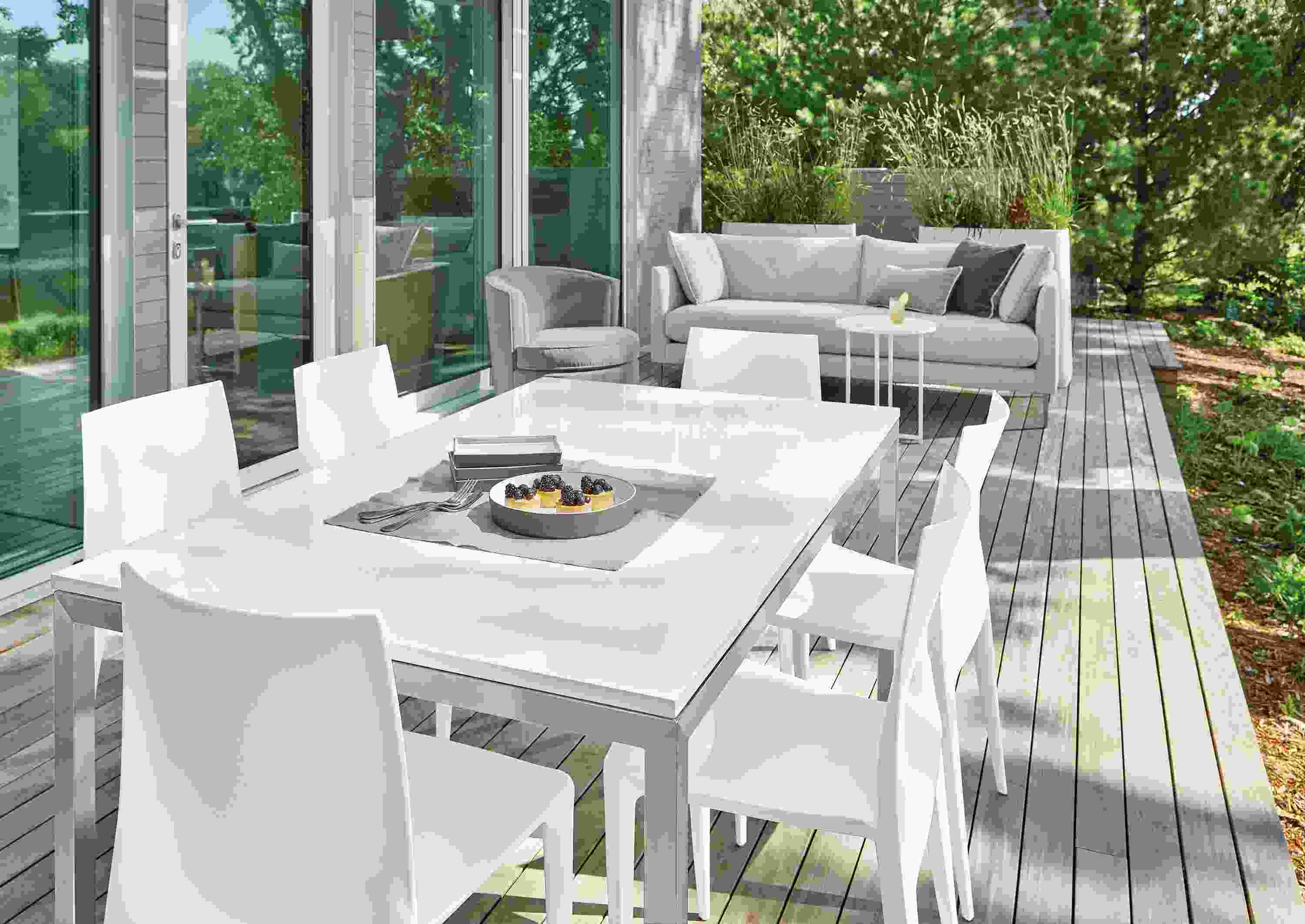 Outdoor space with Parsons table in stainless steel with quartz top, Bellini chairs in white, Palm sofa, Ambrose swivel chair.