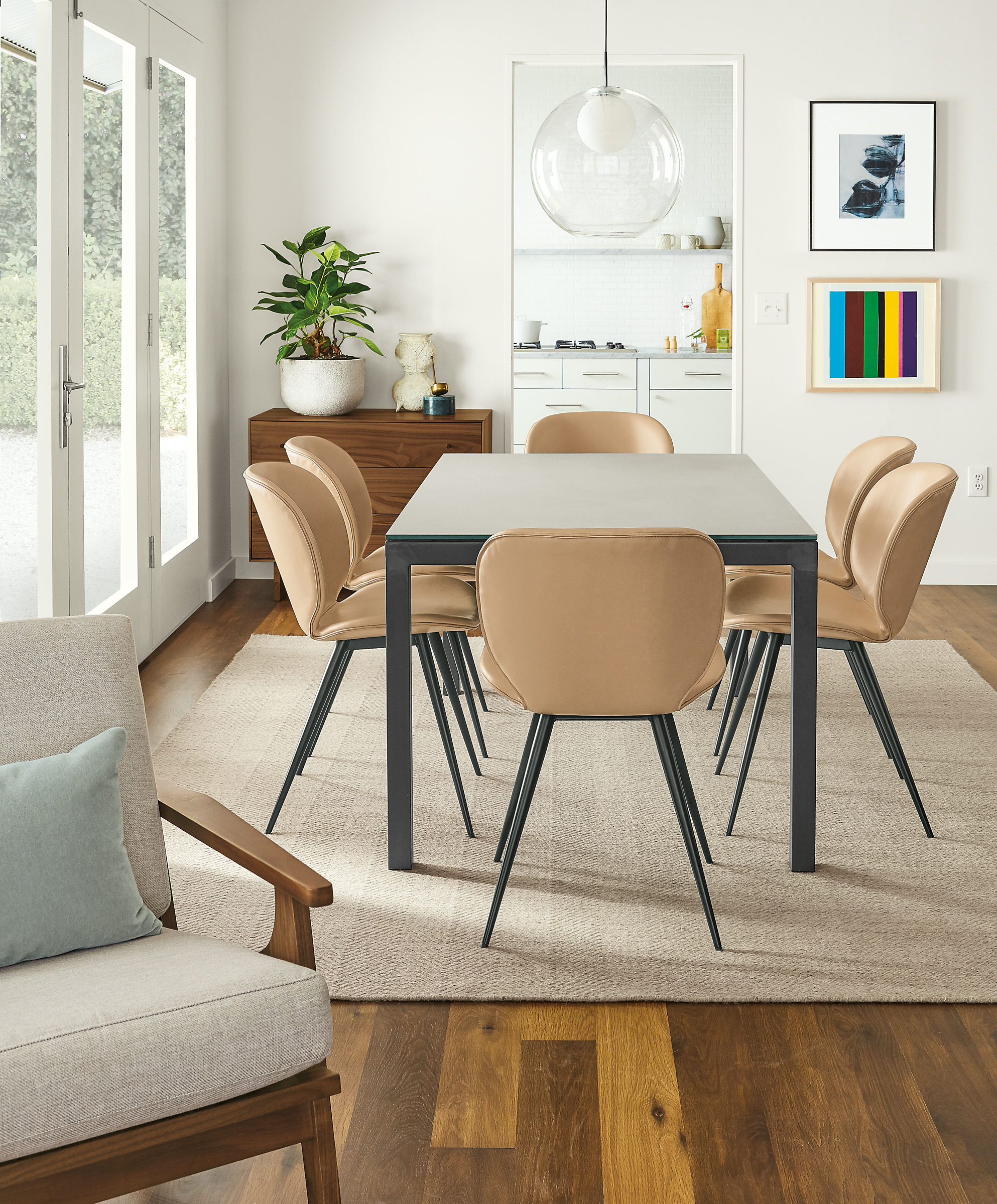 Detail of Parsons table with taupe ceramic top and natural steel base with Gwen synthetic leather side chairs.