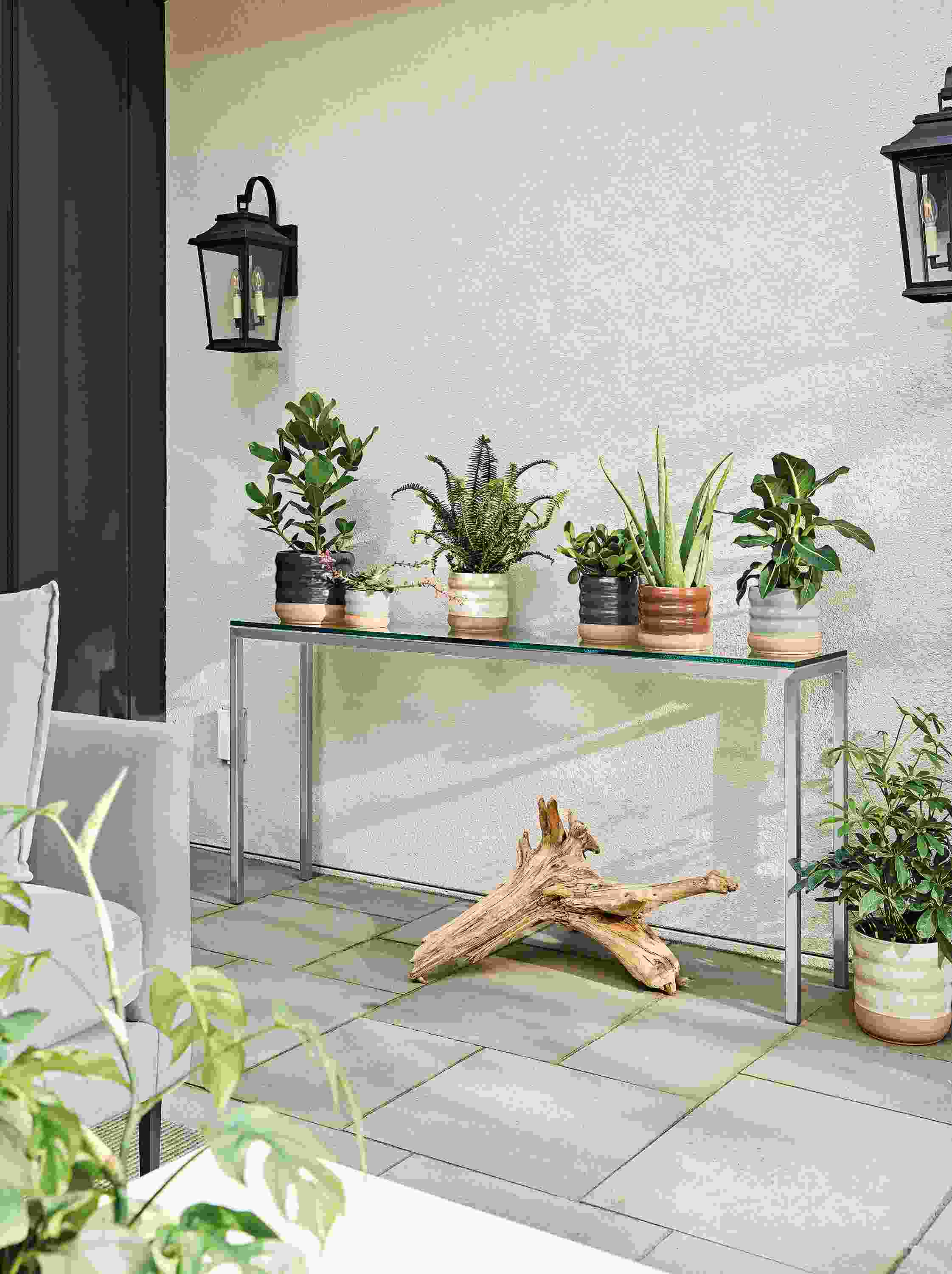 Outdoor patio with parsons table in stainless and clear glass and various elias round planters.