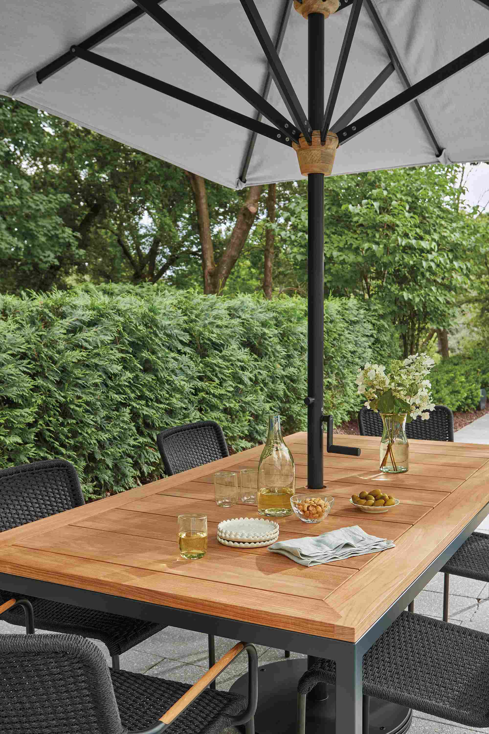 Detail of parsons table in graphite and teak heartwood and Banda patio umbrella in Halo Grey.