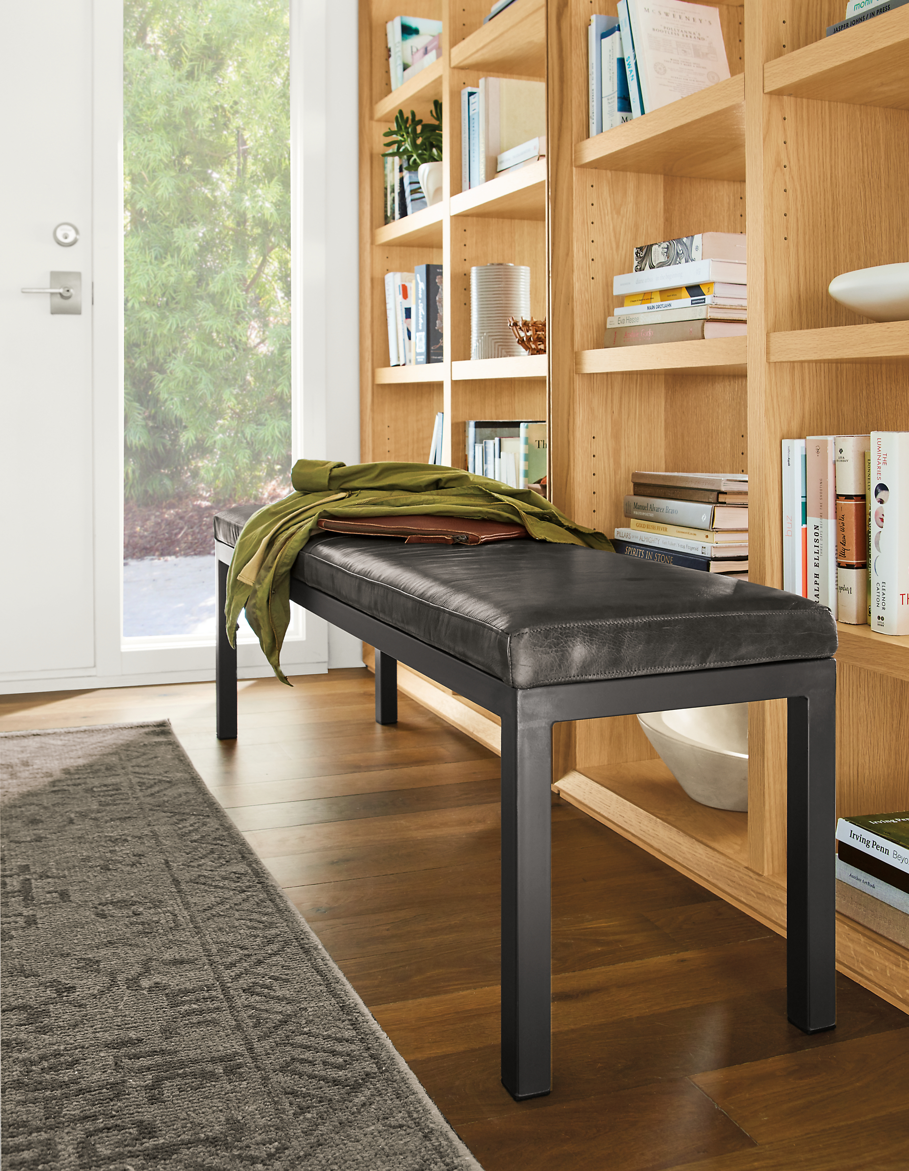 Detail of Parsons bench in vento smoke leather in entryway with Lennox bookcases.