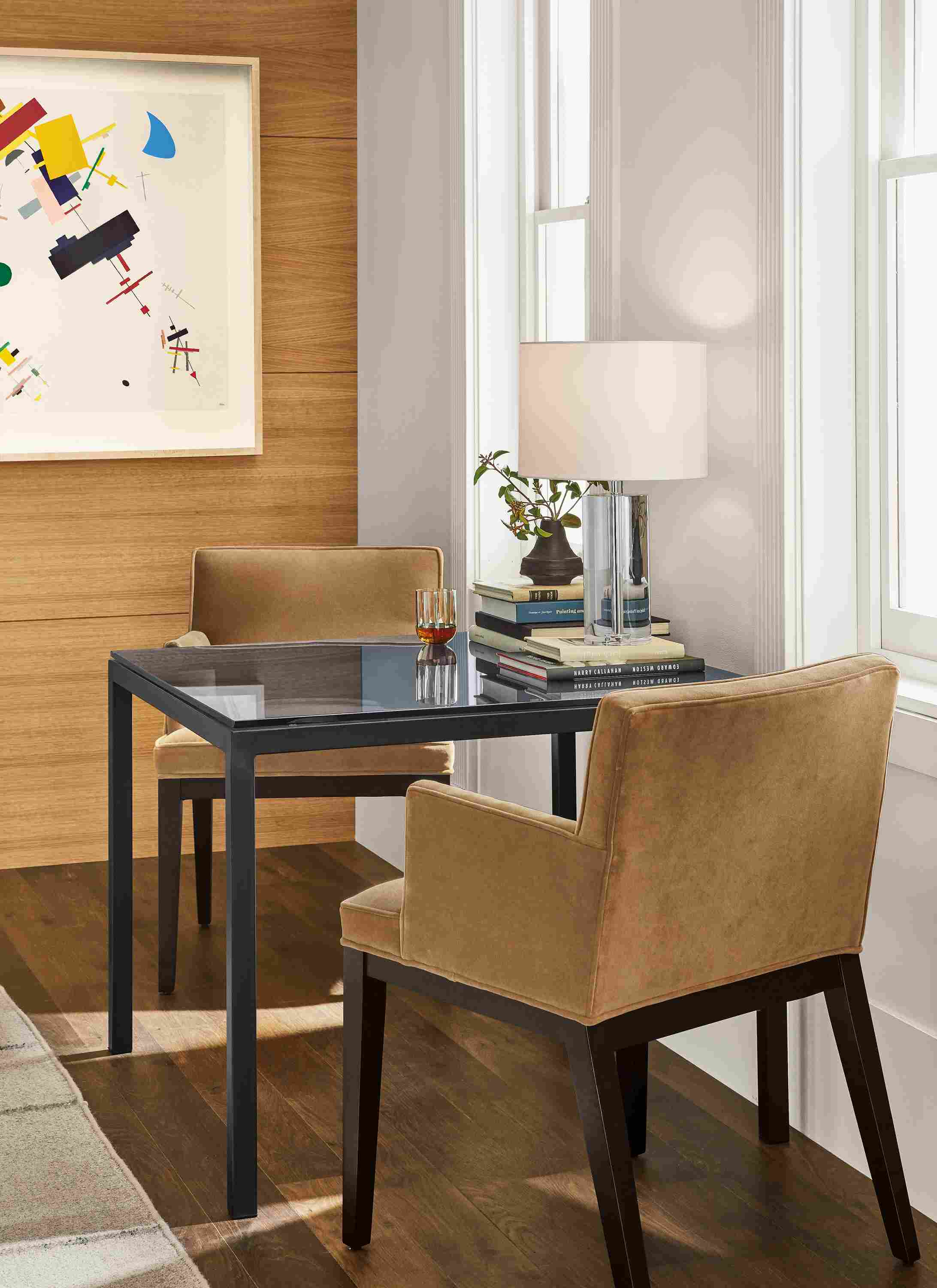 Detail of Parsons table with smoke glass top and natural steel base with two Ansel arm chairs.