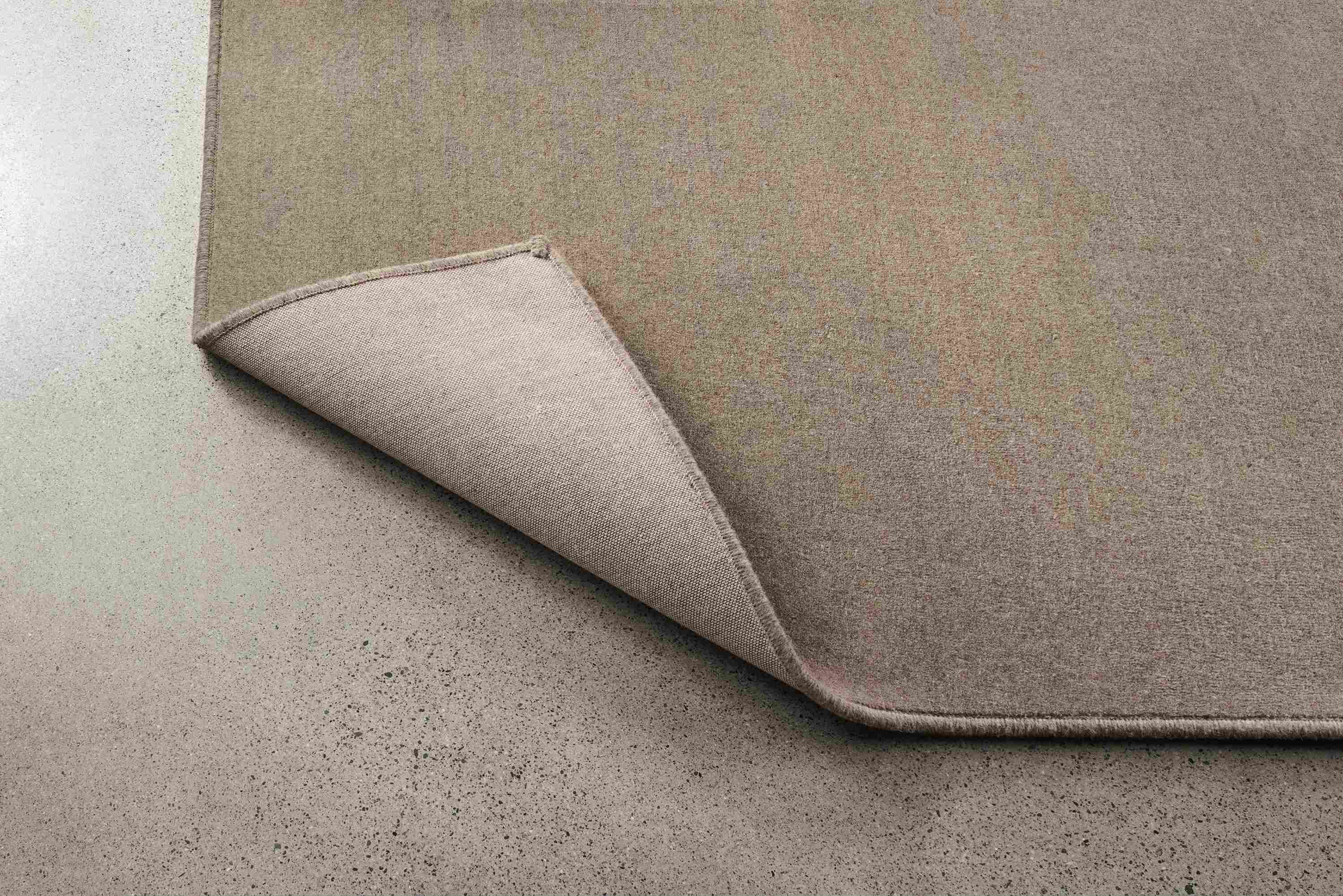 Passage 8 by 10 rug in grey shown with corner flipped up to show underside of rug.