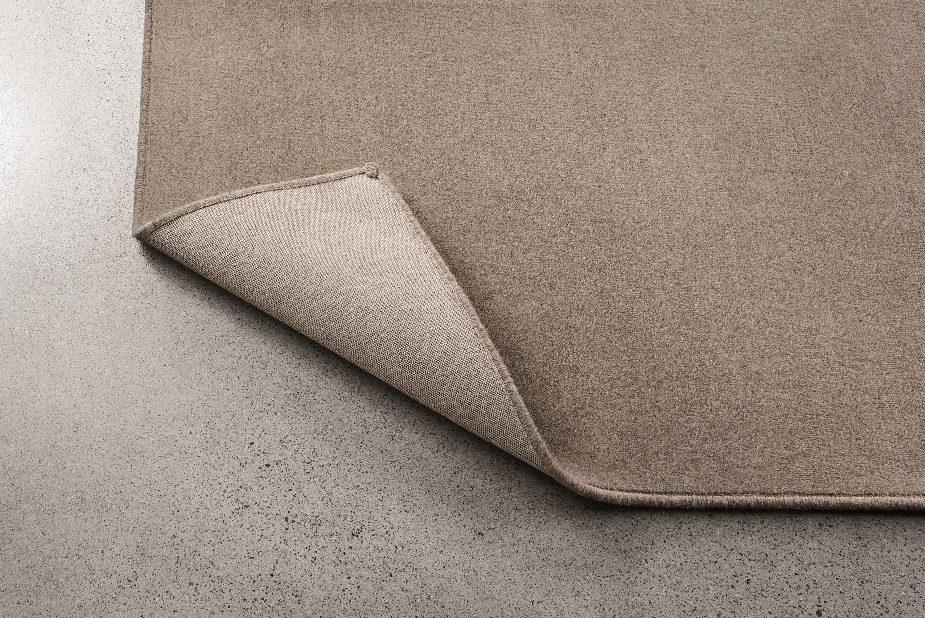 Passage 8 by 10 rug in grey shown with corner flipped up to show underside of rug.