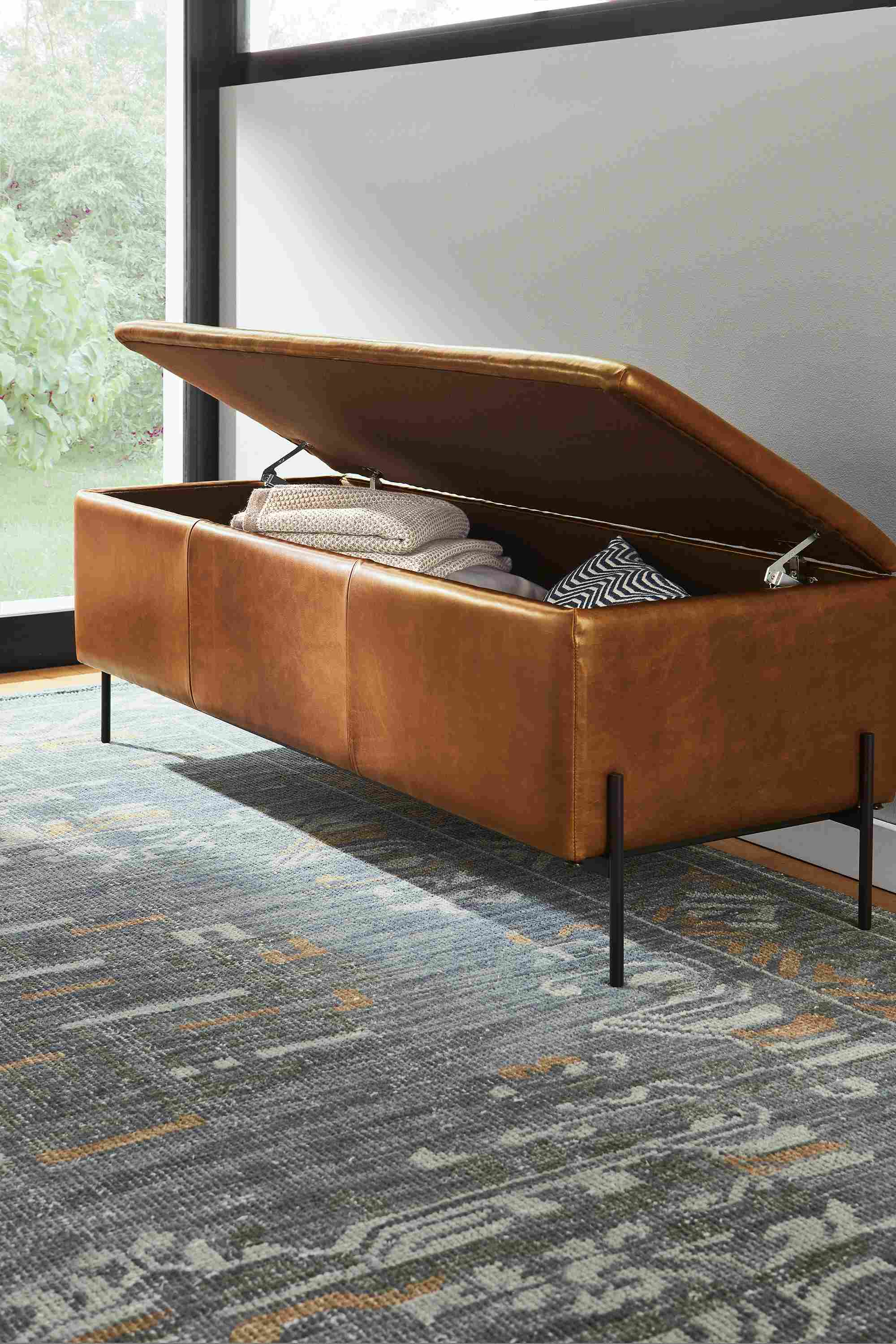Entryway with Paxton storage ottoman in Vento Cognac leather shown with top open and Amira 8 by 10 in Ocean.