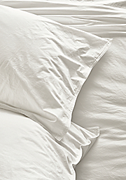 Detail view of Signature Percale standard sham and fitted sheet in white.